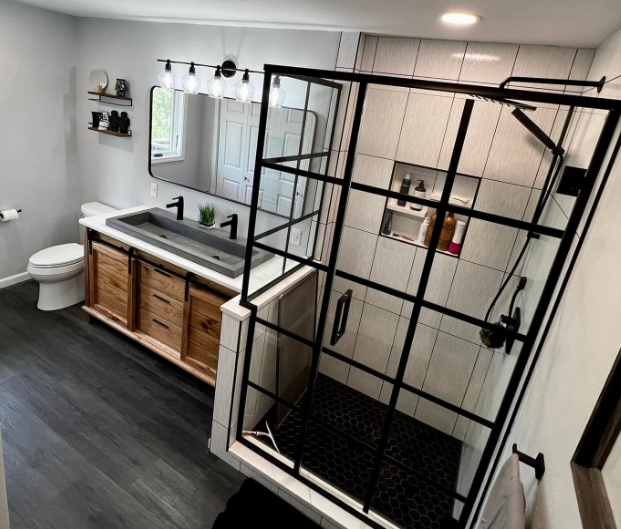 Modern bathroom with walk-in black glass shower, double vanity, toilet, and gray flooring