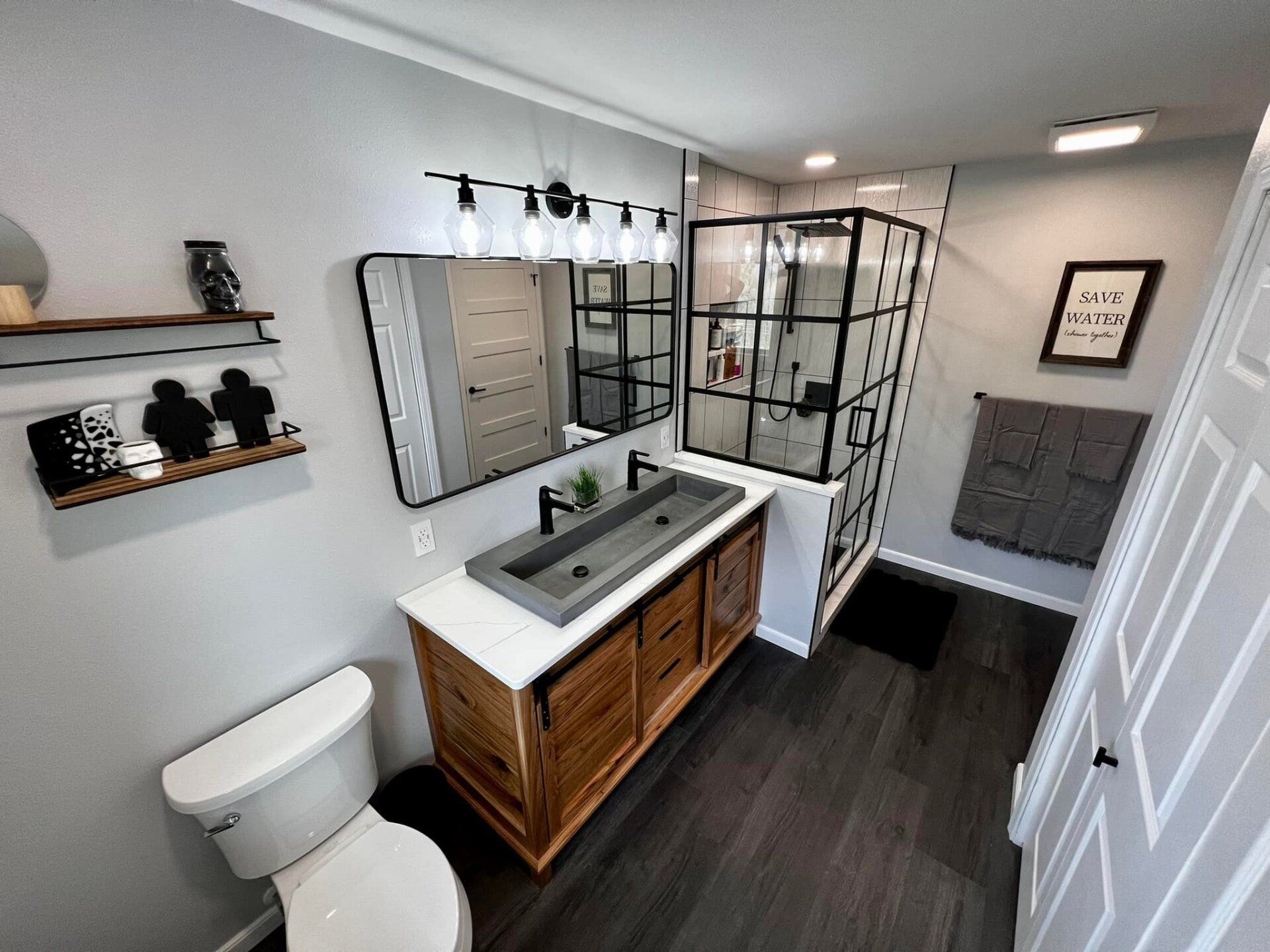 Modern bathroom with vanity, toilet, glass shower, and dark wood flooring