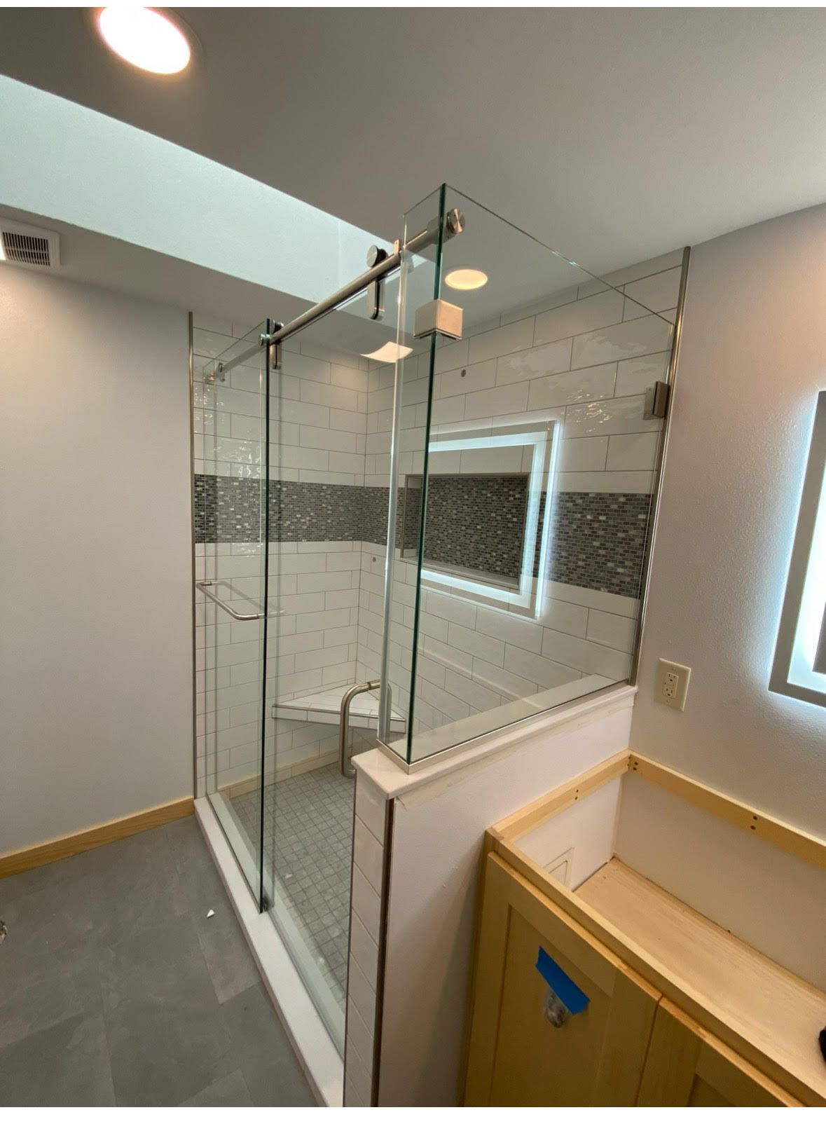 Modern bathroom with glass-enclosed shower, tiled walls, and a wooden vanity cabinet