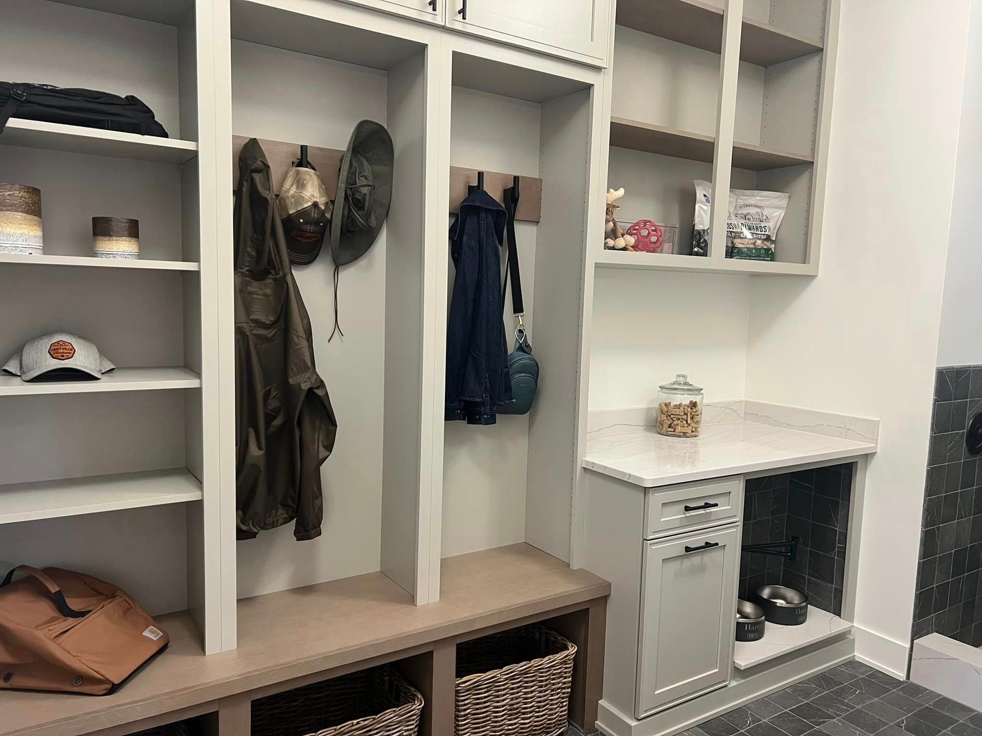 Built-in mudroom cubbies with coats, baskets, bench seating, and a small cabinet on the right