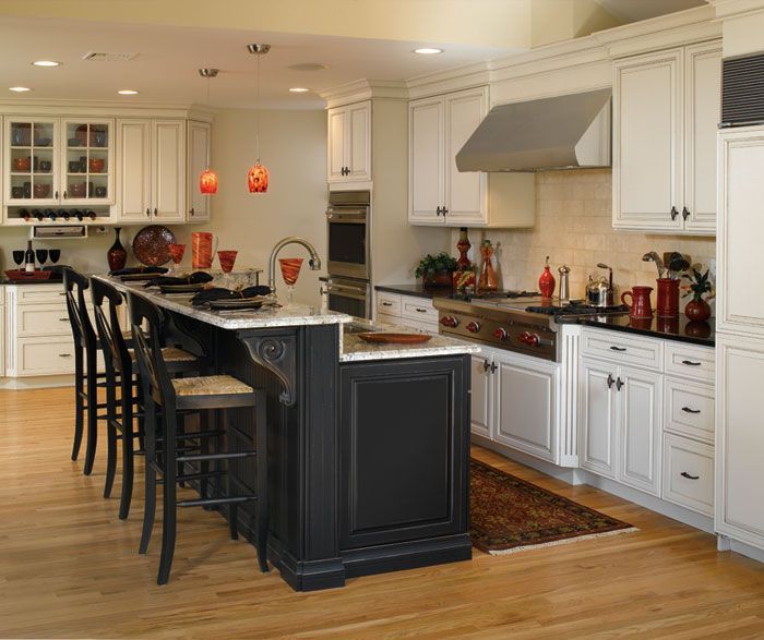 Bright modern kitchen with white cabinets, dark island, bar stools, and hardwood floors