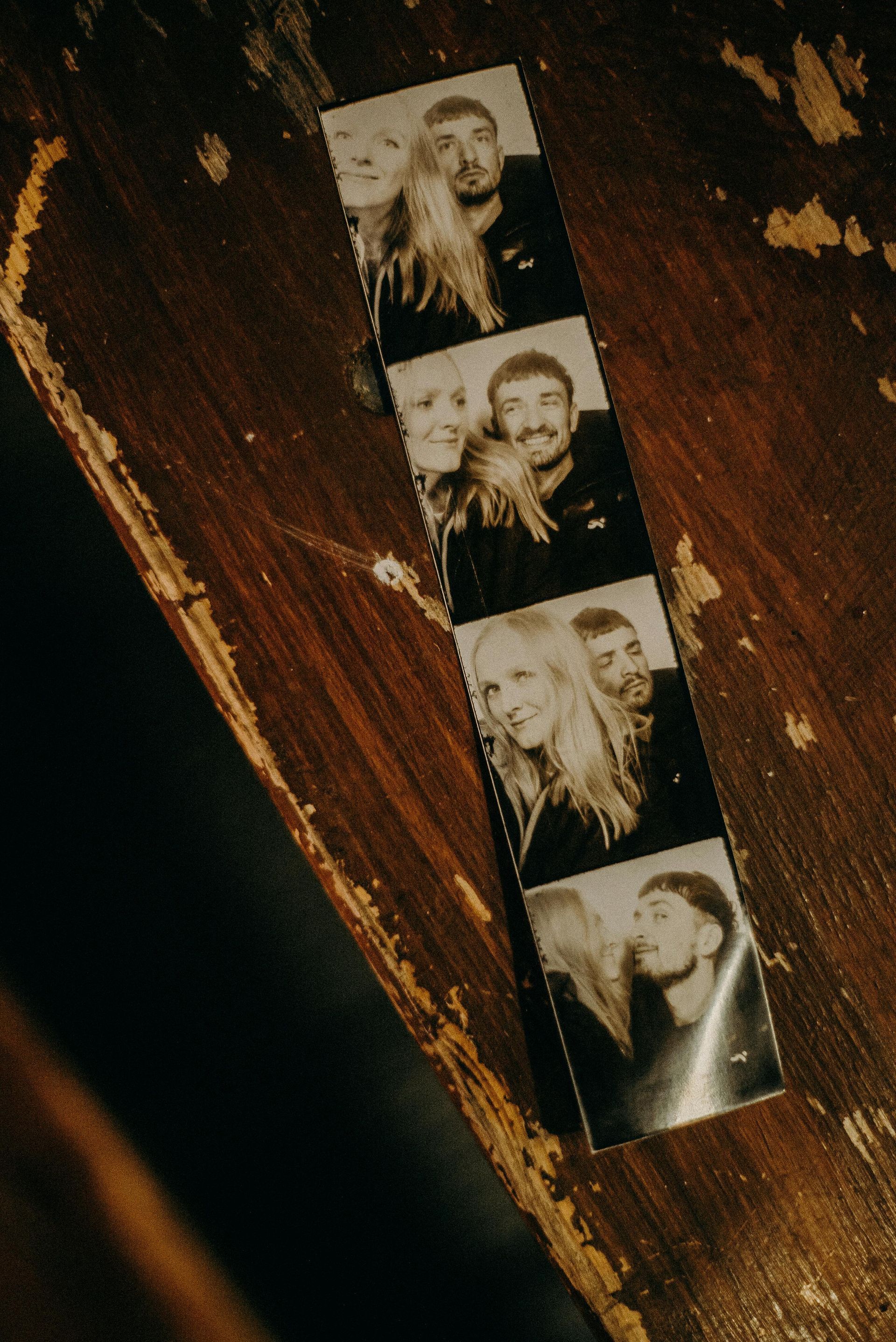 Four-photo strip on a wooden table, showing black-and-white portrait snapshots.