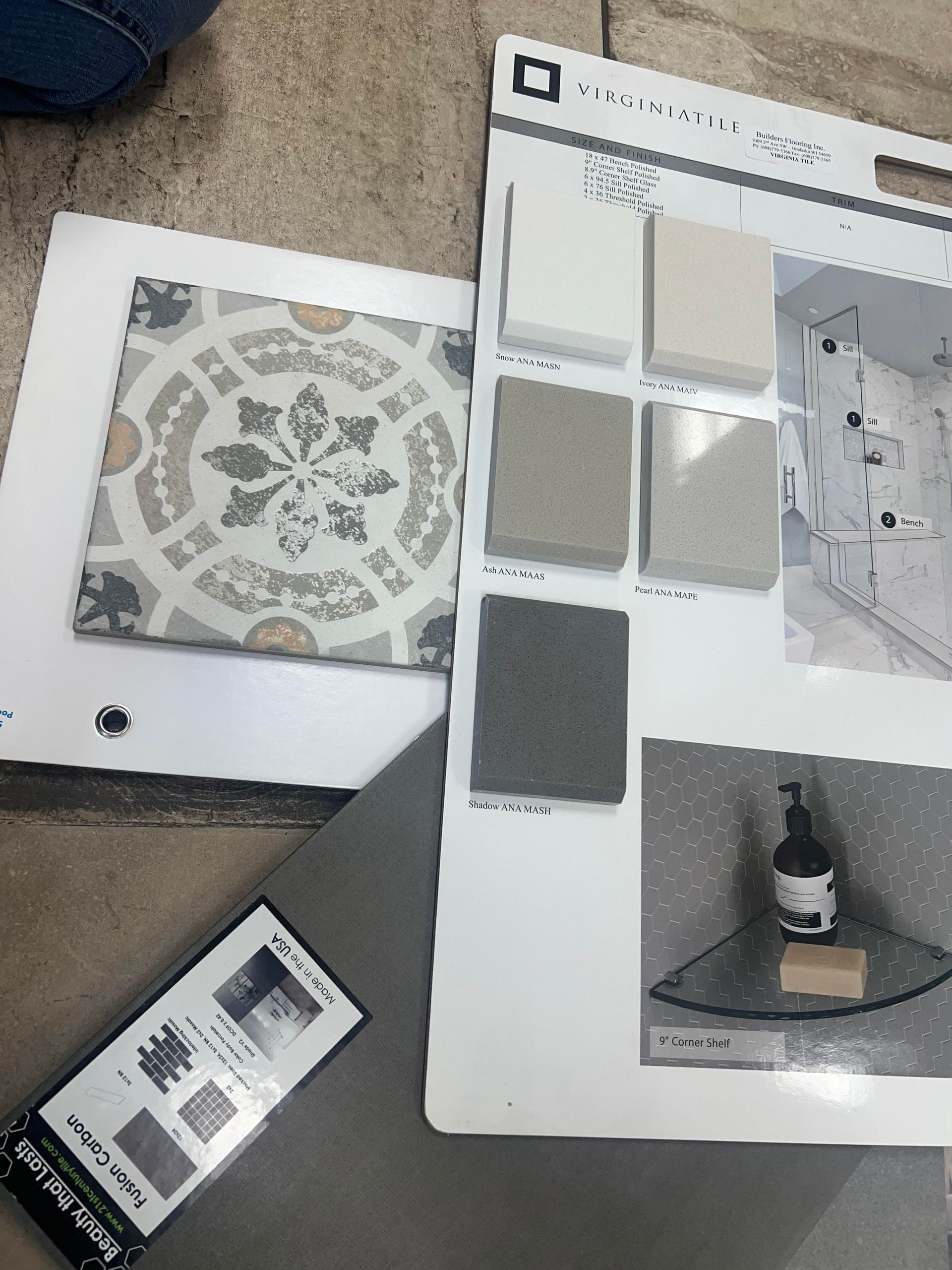 Paint sample boards and tile samples arranged on a carpeted floor, with a decorative circular tile design and gray swatches.