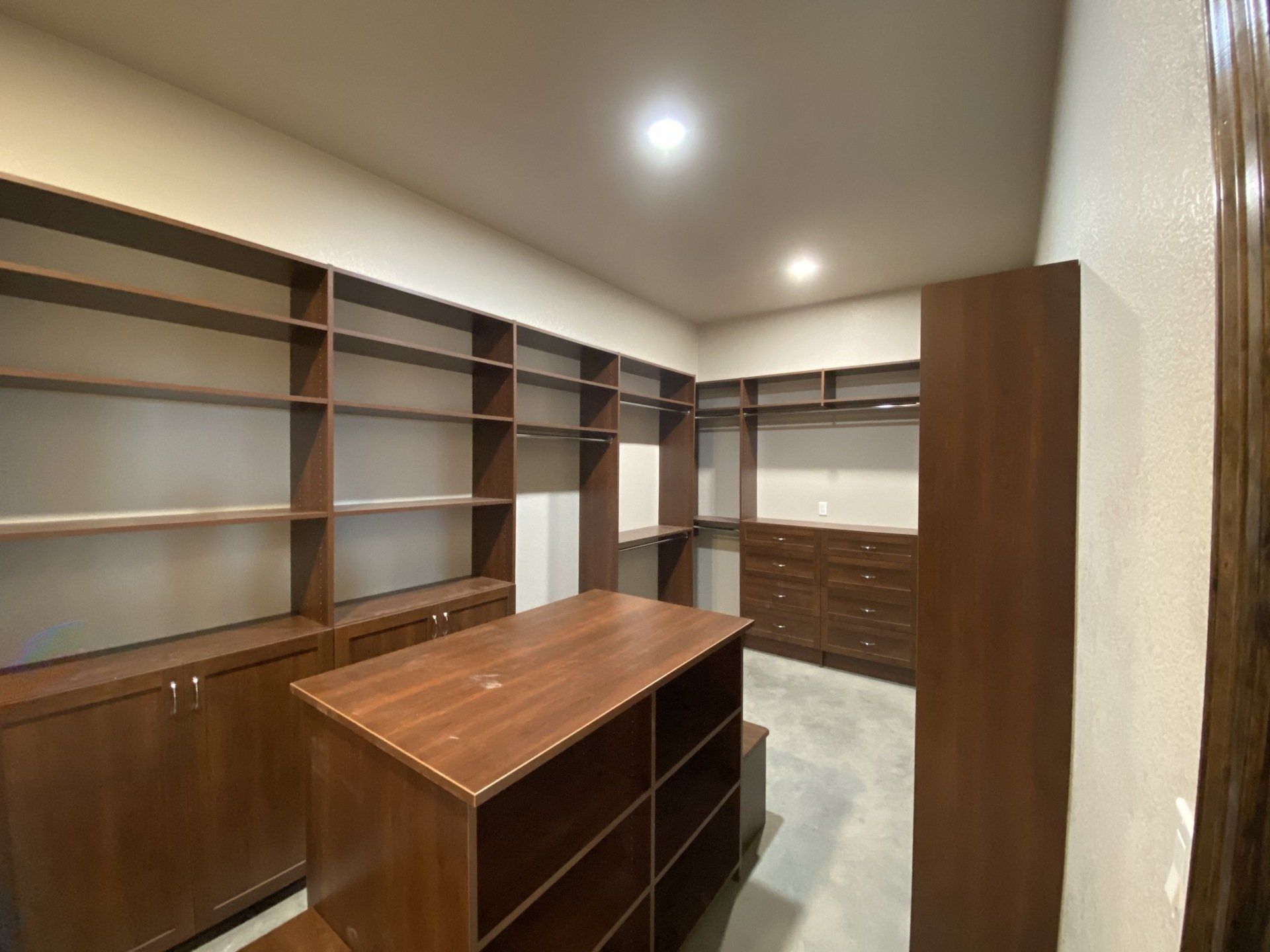 A large walk in closet with lots of shelves and drawers.