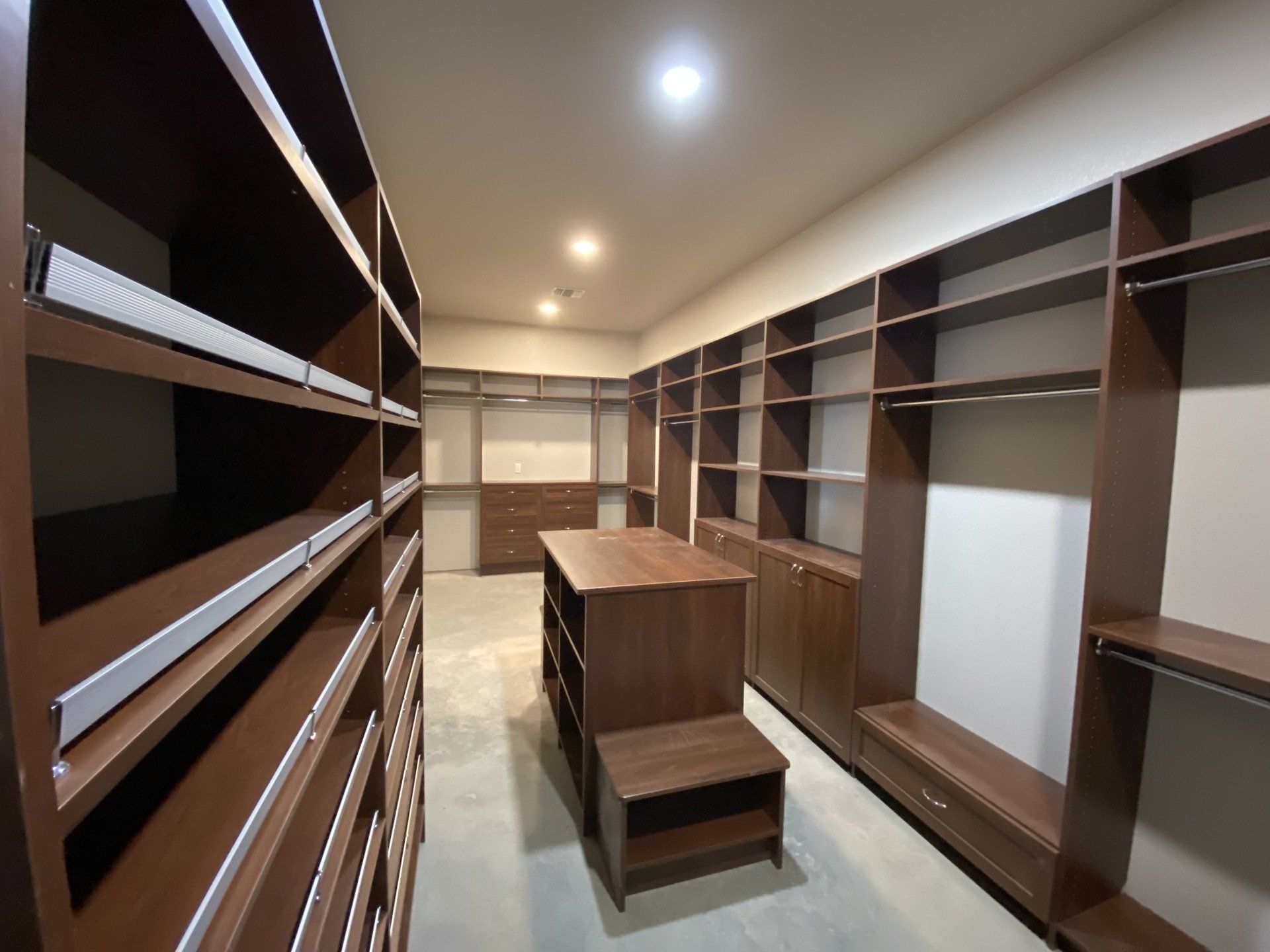 A walk in closet with lots of shelves and drawers