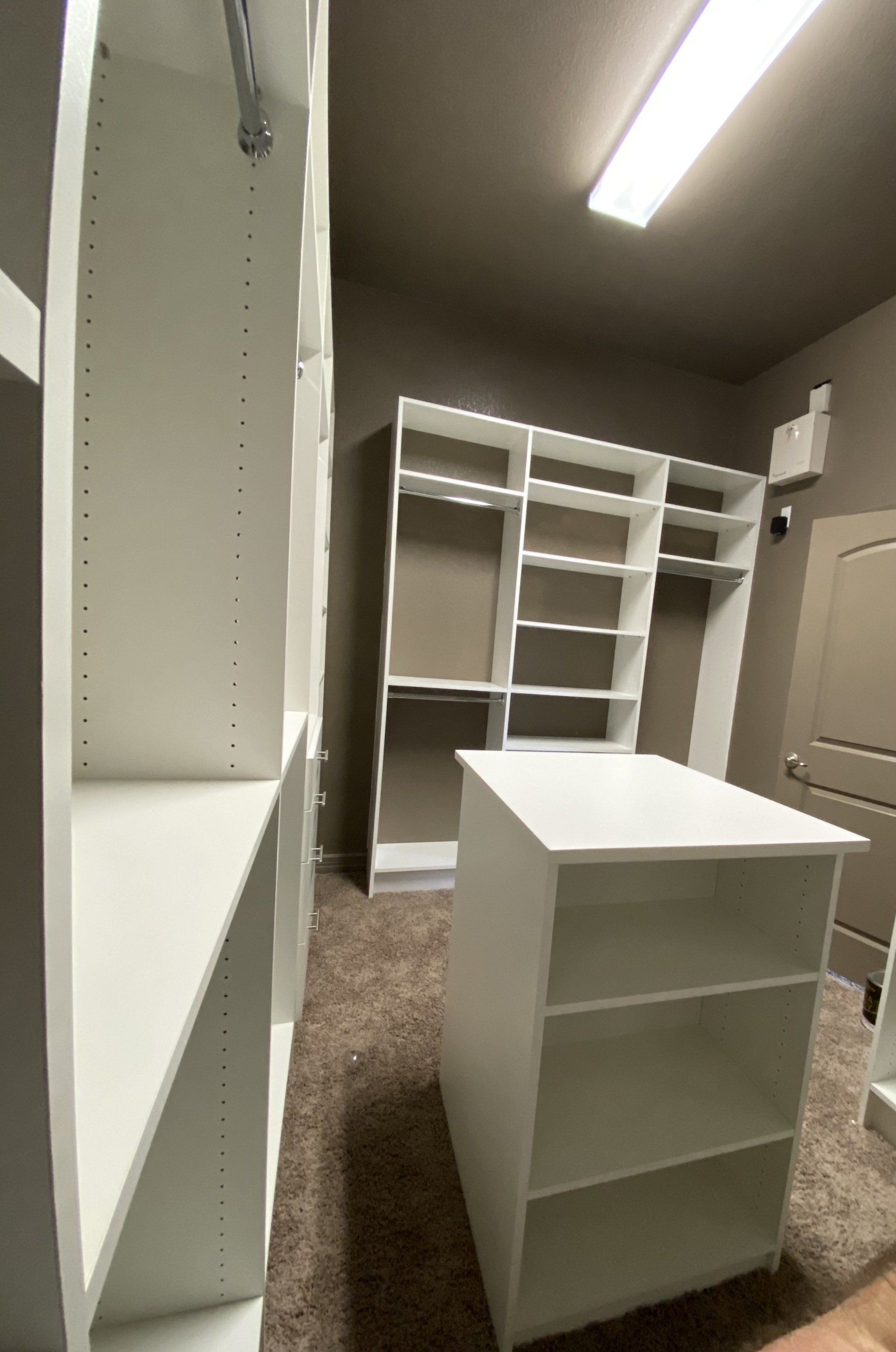 A walk in closet with lots of shelves and a table.