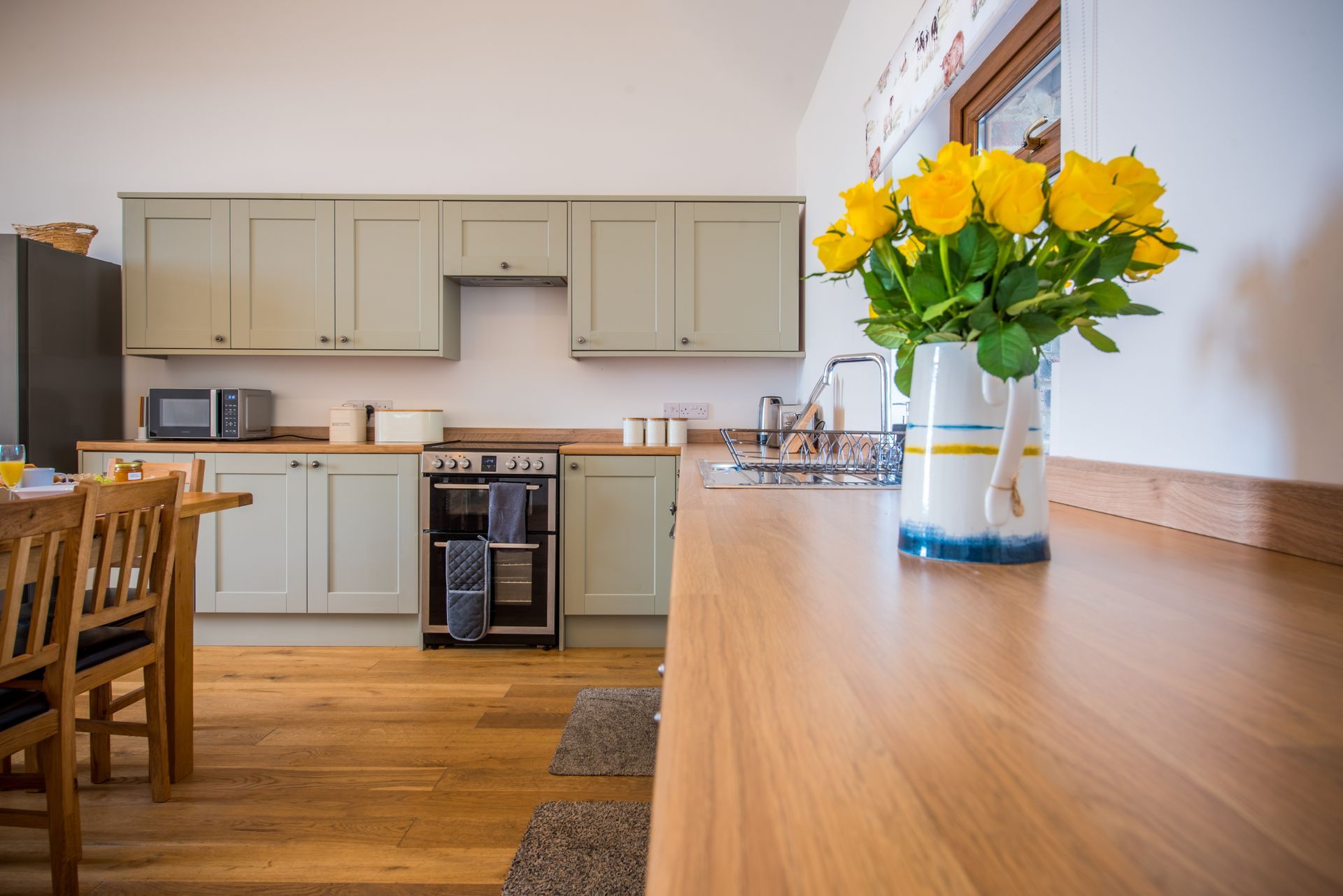 Kitchen table with yellow flowers at The Cowshed holiday cottage, Green Grove Barns.