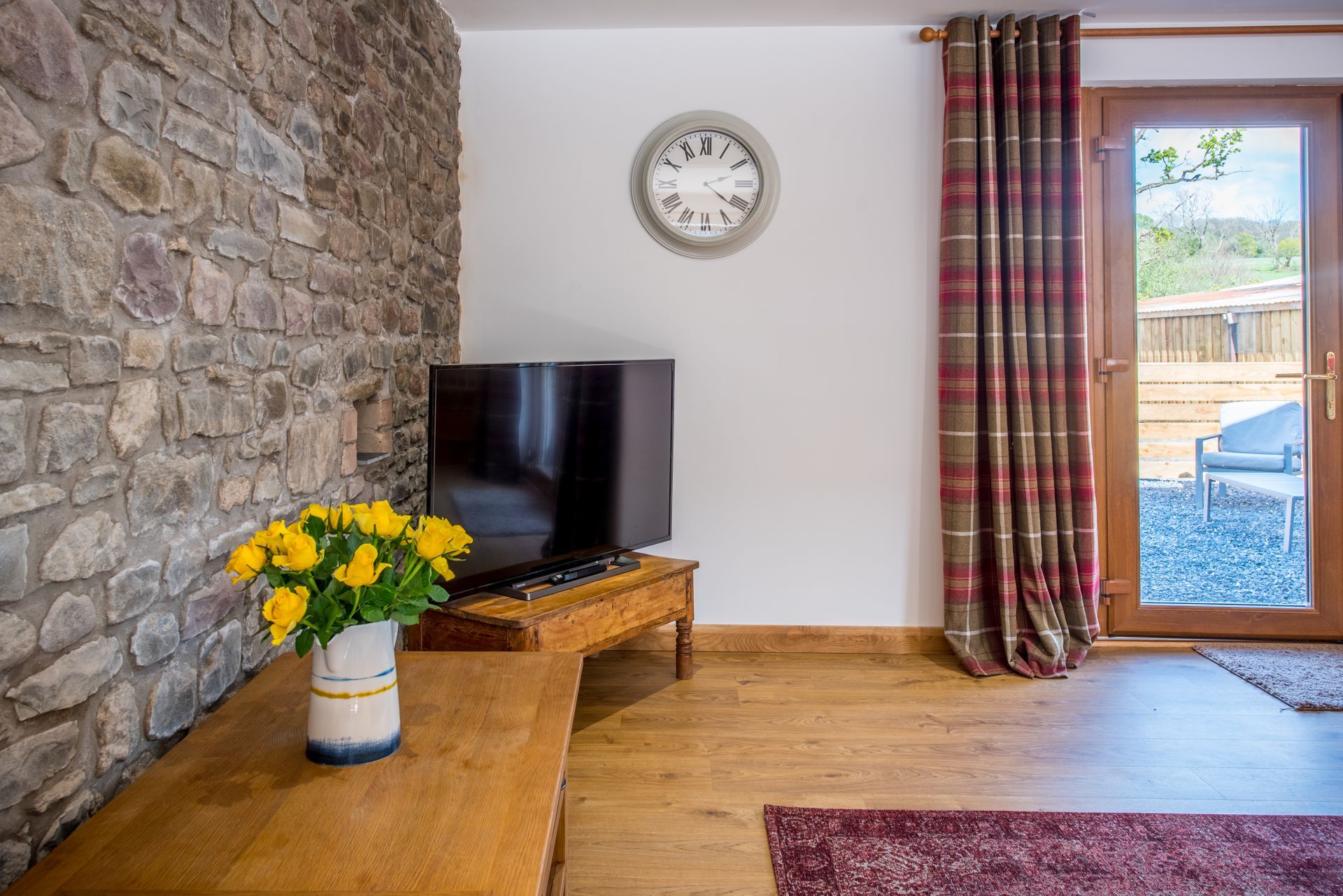 Cosy lounge with fireplace and floral arrangement at The Coach House, Green Grove Barns.