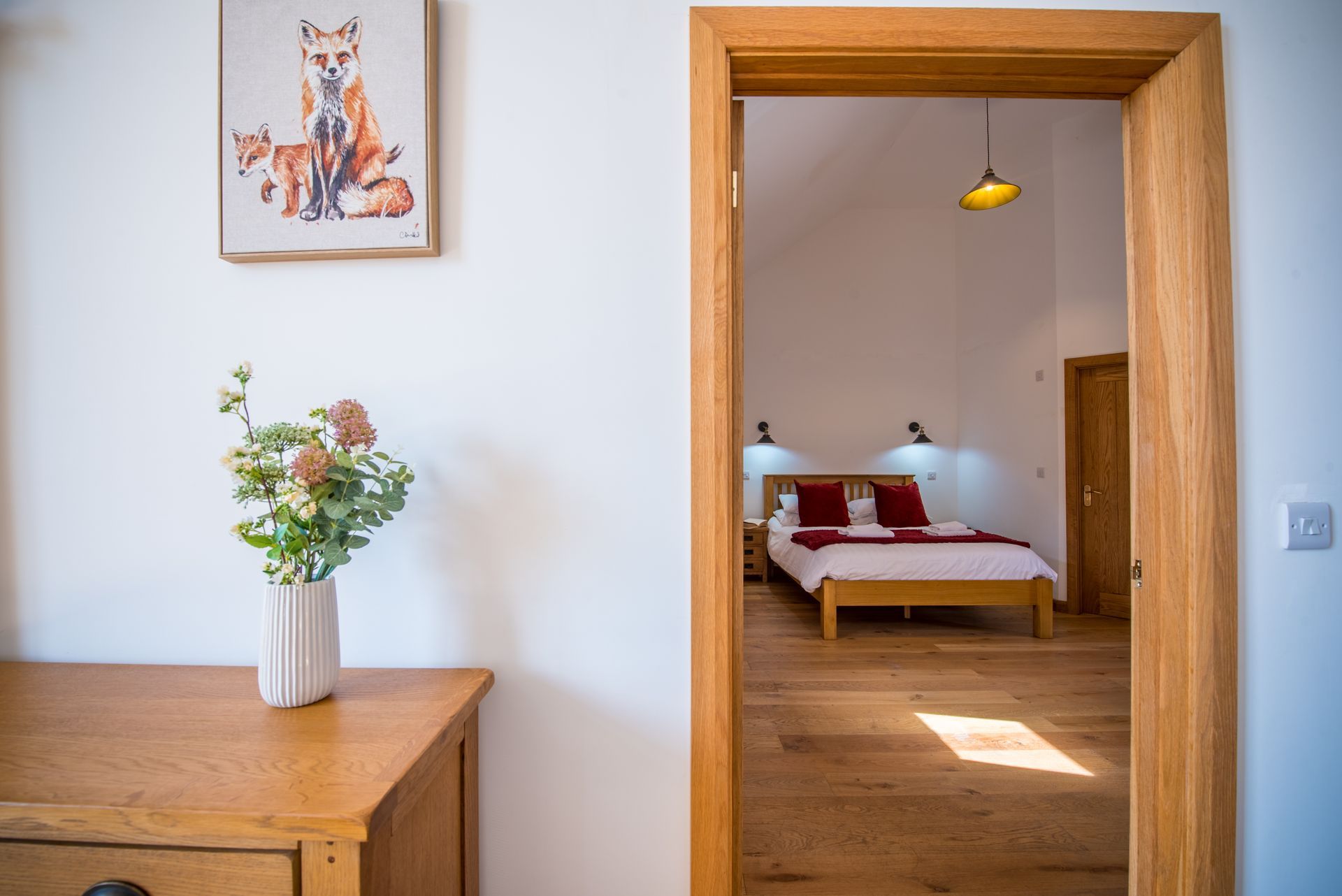 Cosy bedroom at The Cowshed, Green Grove Barns with rustic décor and soft lighting.