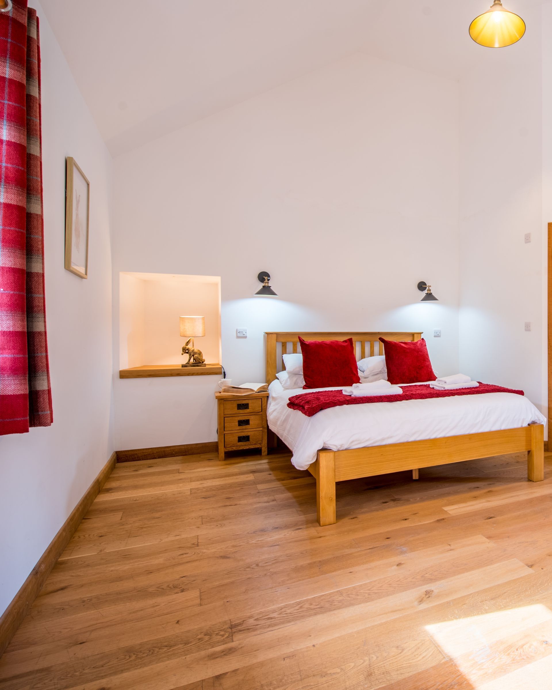 Bright double bedroom at The Cowshed featuring wooden beams and neutral décor.