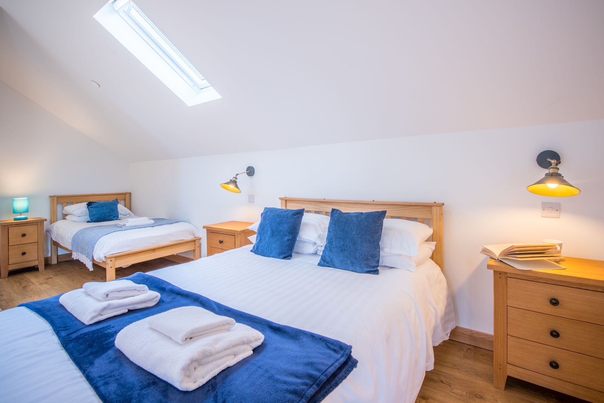 Twin bedroom in The Coach House with skylight and soft blue bedding.