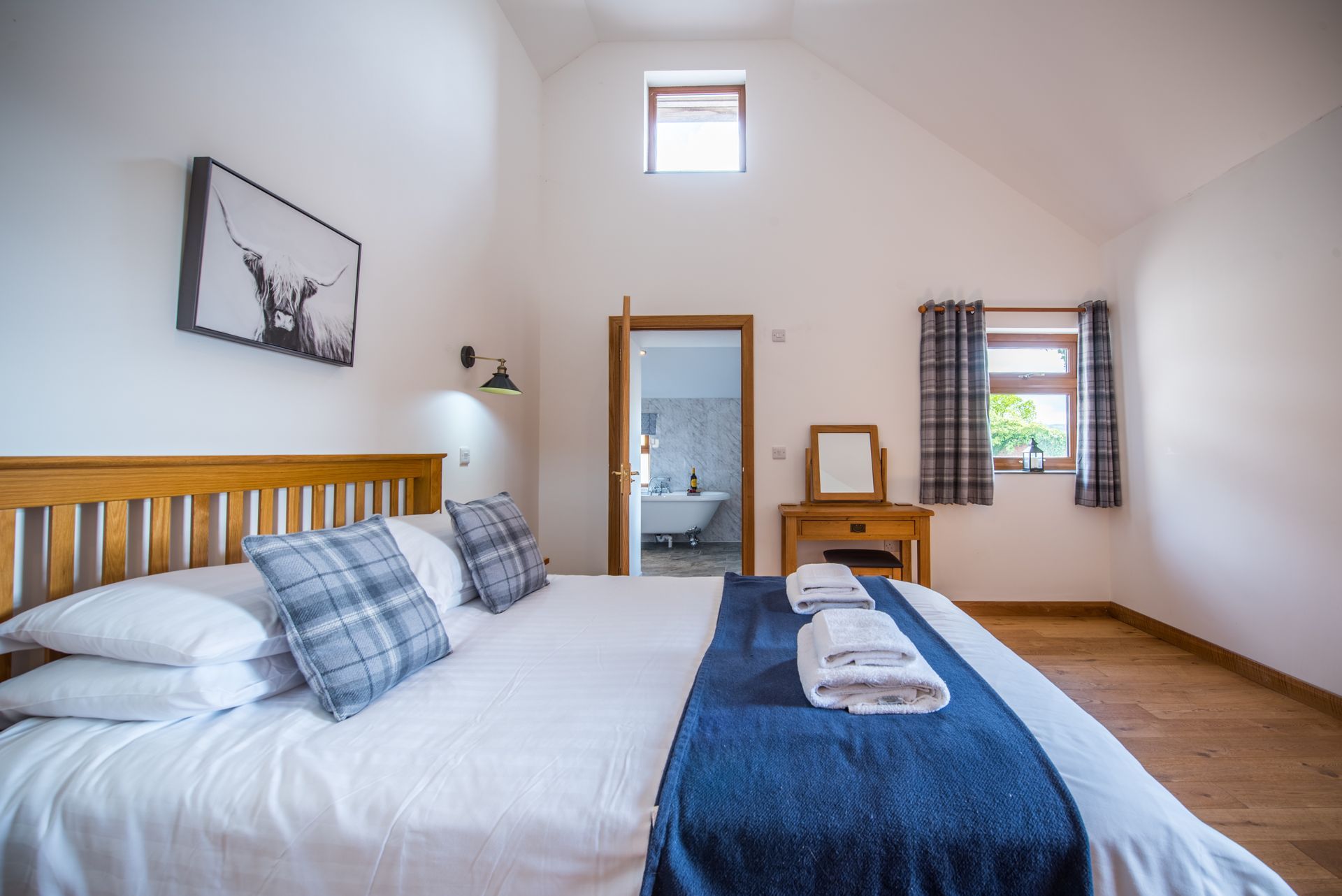 Spacious bedroom at The Cowshed with countryside views through large windows.