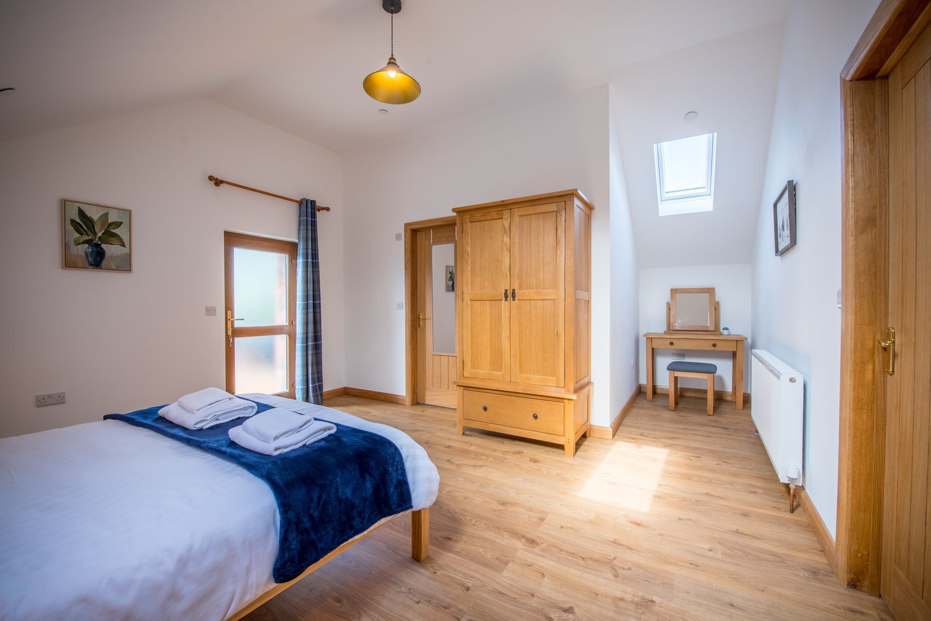Bedroom with natural wood furniture and neutral tones at The Coach House, Carmarthenshire.