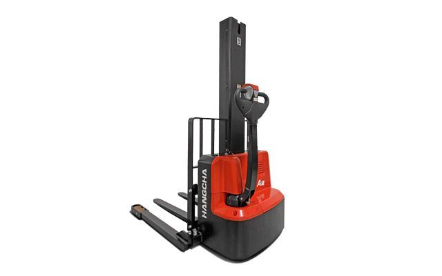 Empileur électrique vertical rouge et noir dans un décor de studio blanc, avec fourches et poignée de commande.