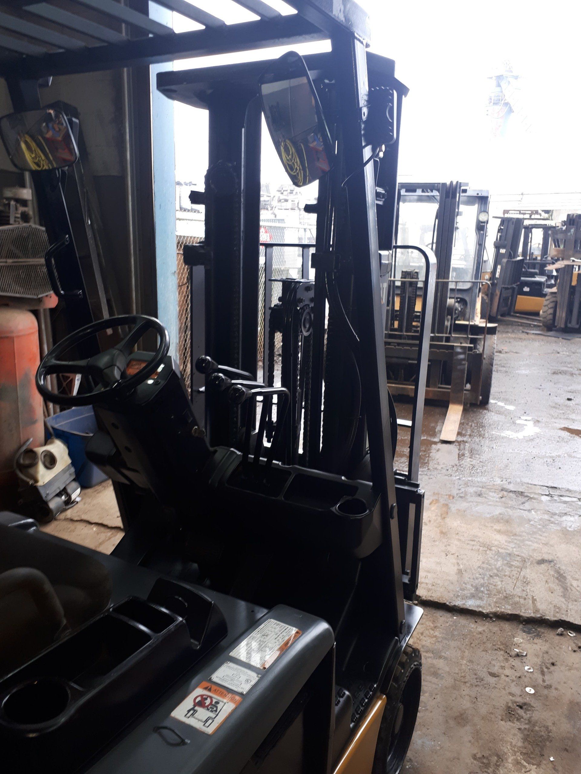 A row of forklifts are parked in a garage