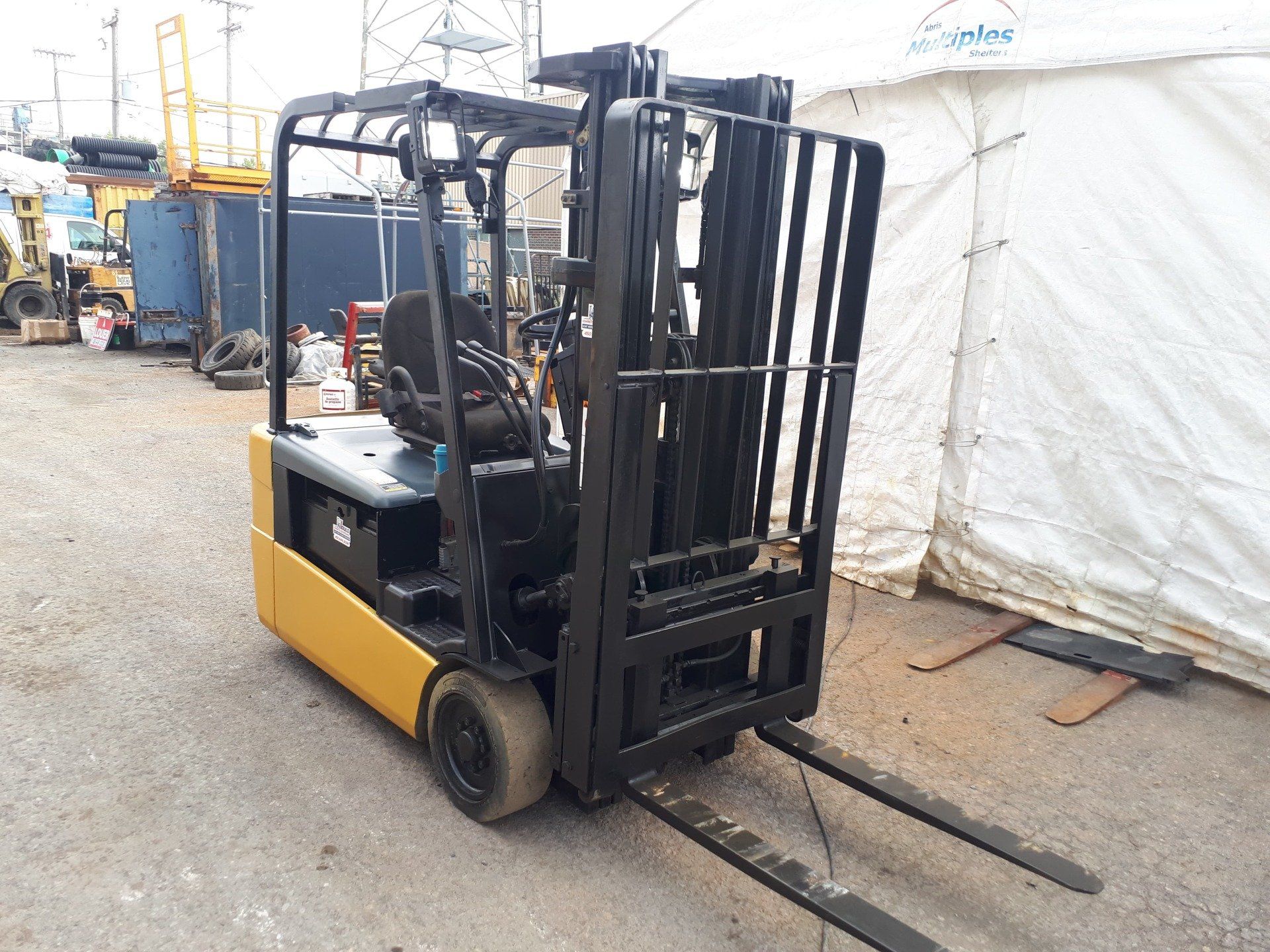 A yellow and black forklift is parked in front of a white tent.