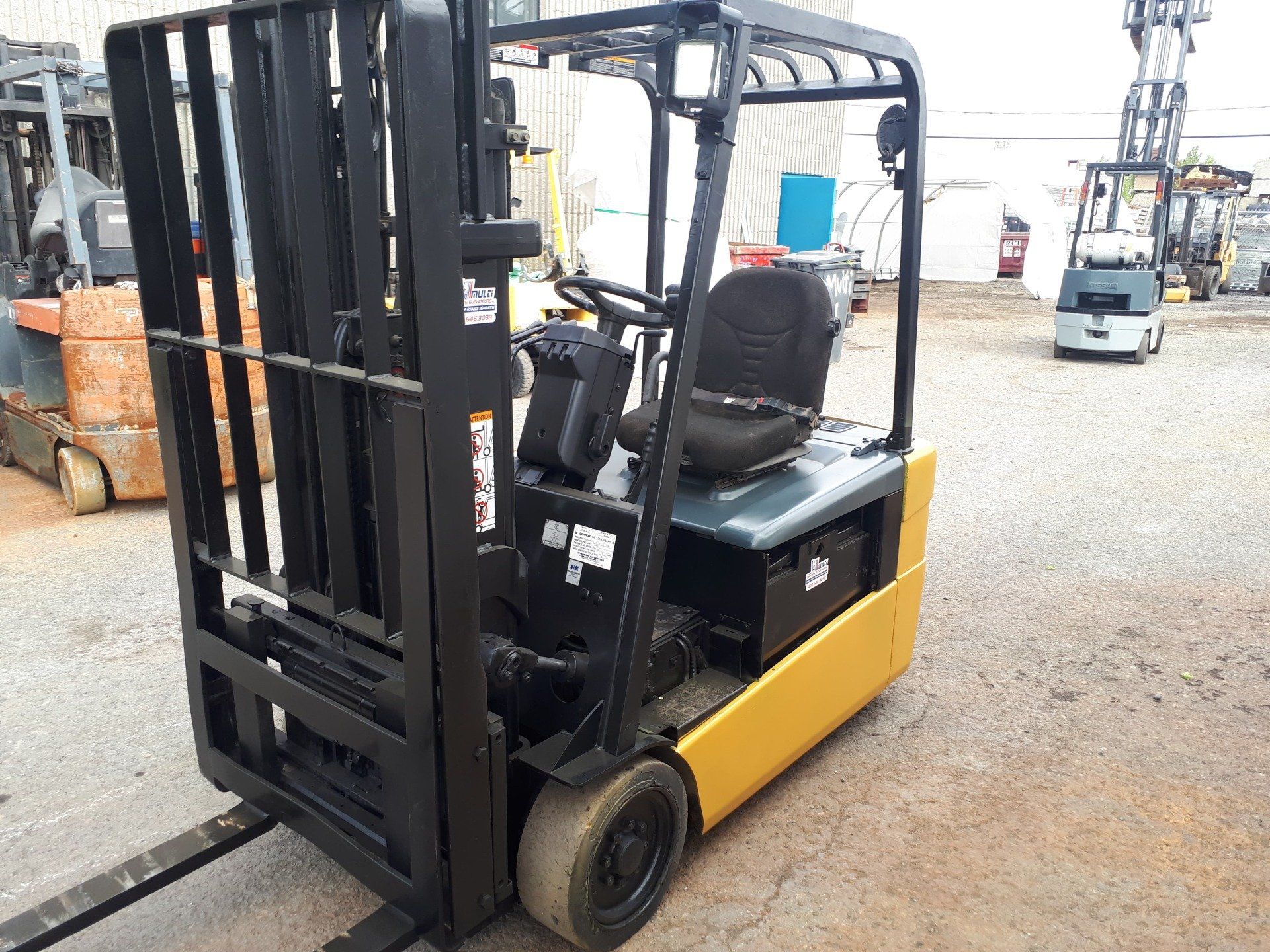 A yellow and black forklift is parked in a parking lot.