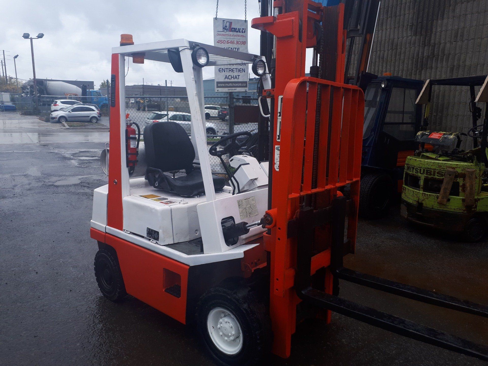 A red and white forklift is parked in a parking lot