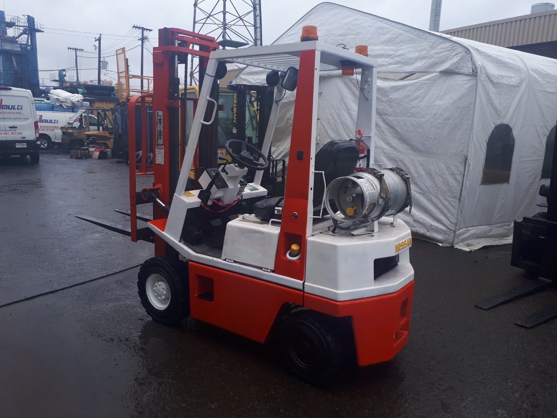 A red and white forklift is parked in front of a white tent.