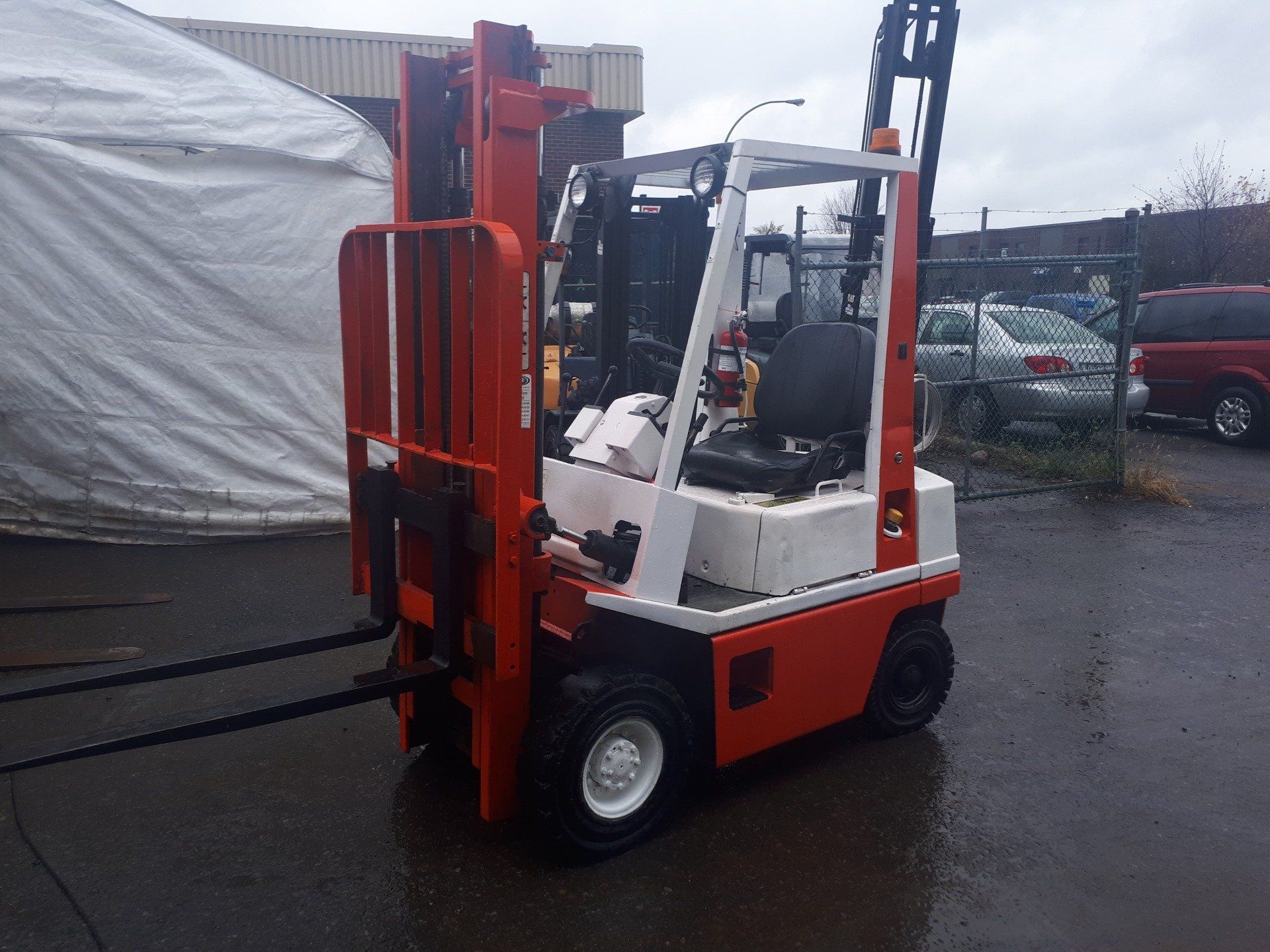 A red and white forklift is parked in front of a white tent