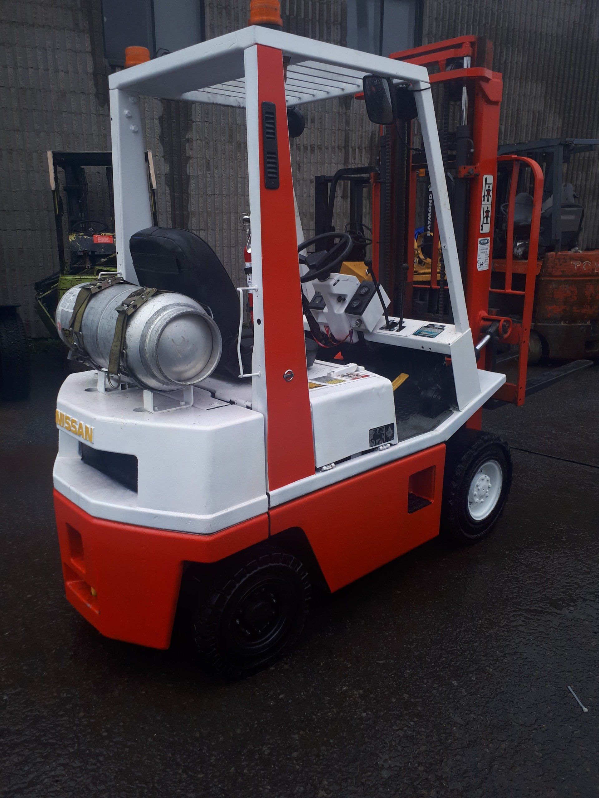 A red and white forklift is parked in a parking lot
