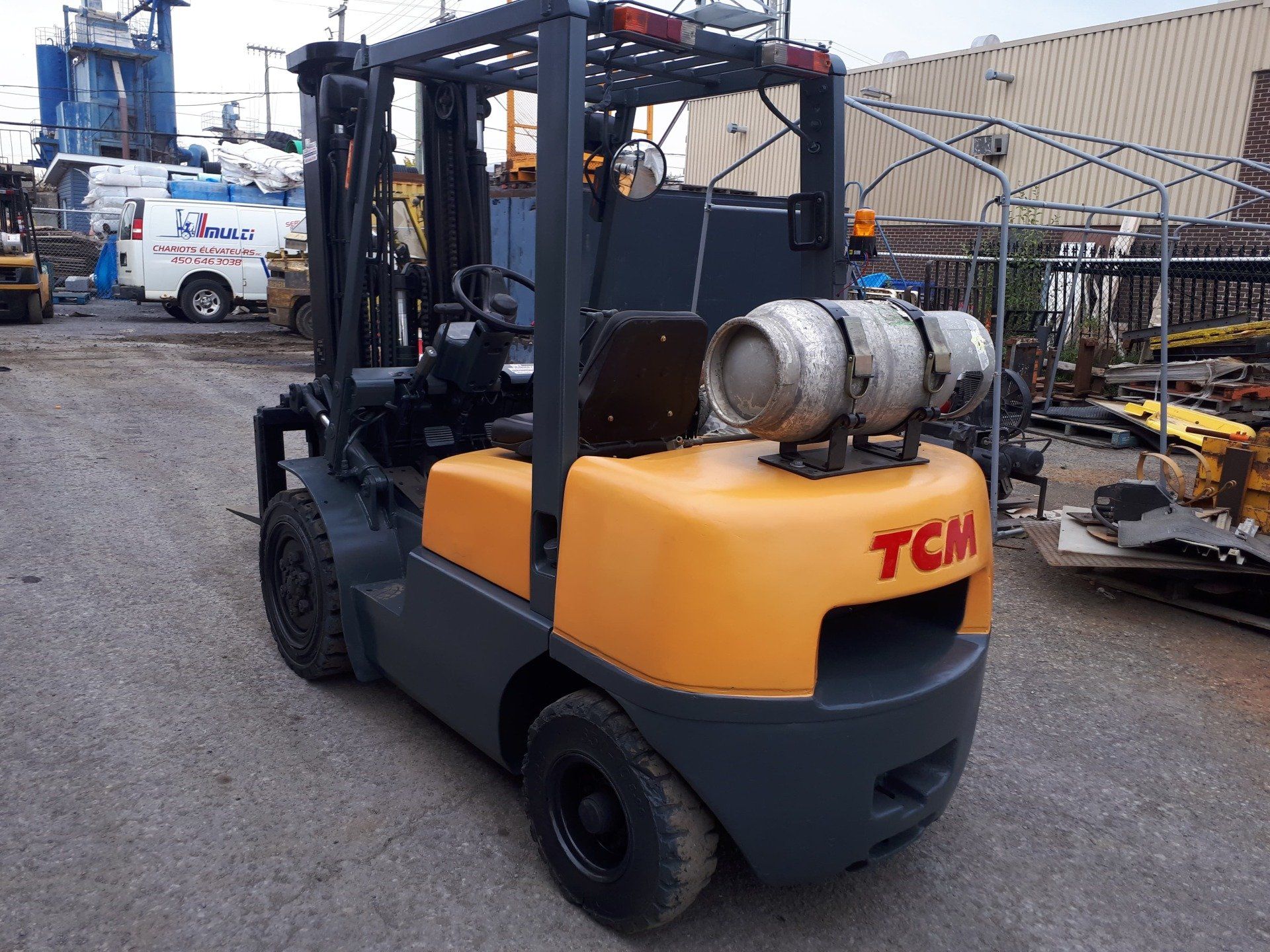 A yellow and gray tcm forklift is parked in a parking lot.