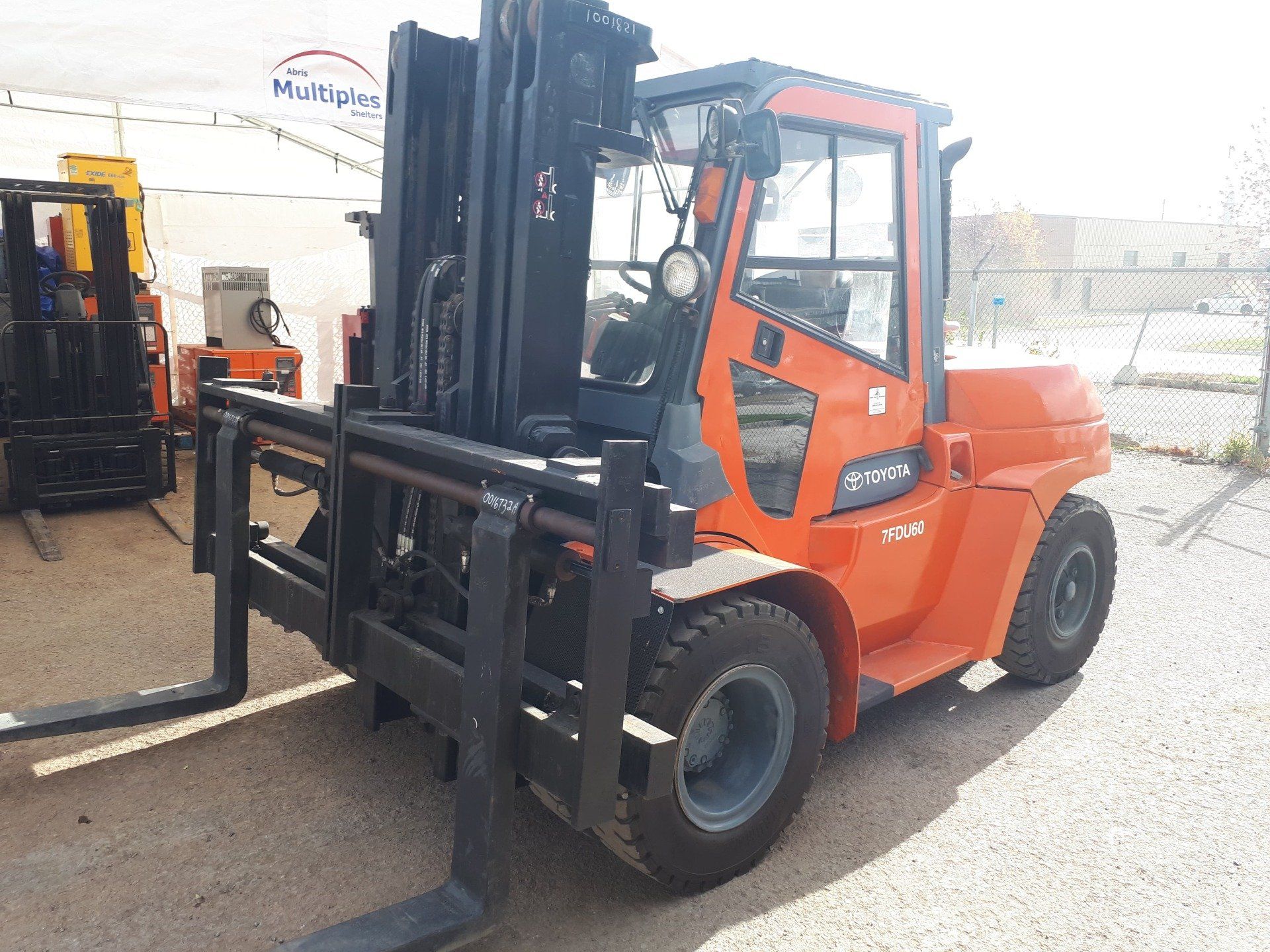 An orange forklift is parked in a parking lot.