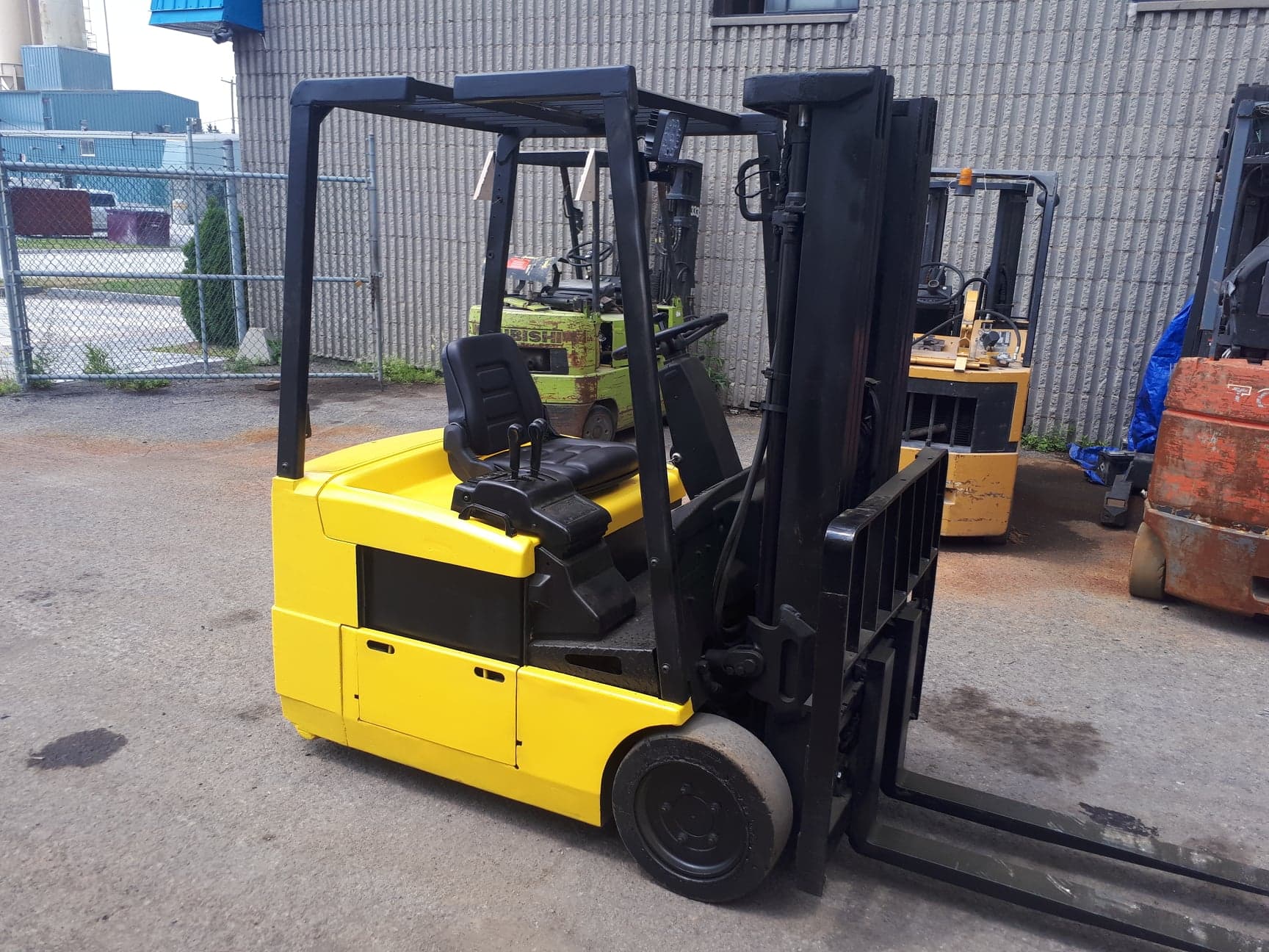 A yellow forklift is parked in front of a building.