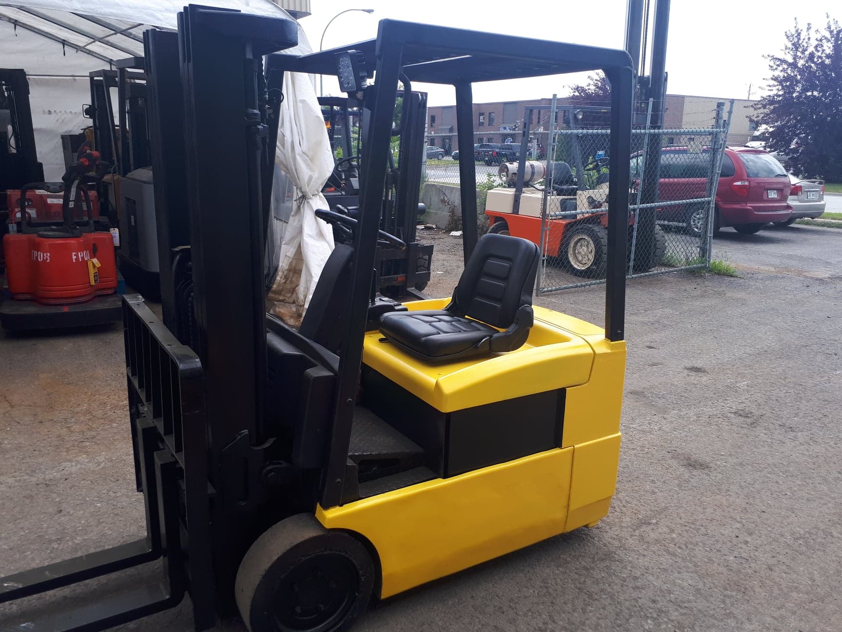 A yellow forklift is parked in a parking lot.