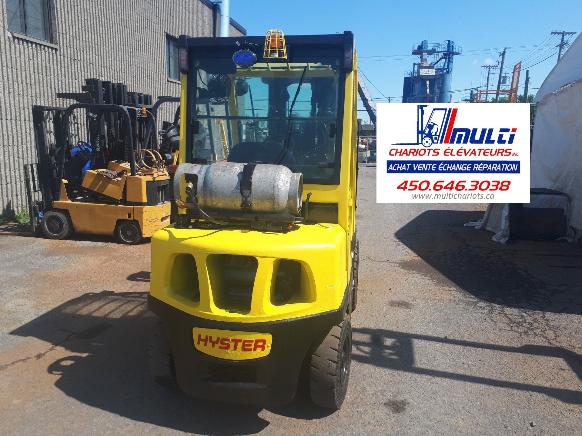 A yellow hyster forklift is parked in front of a building