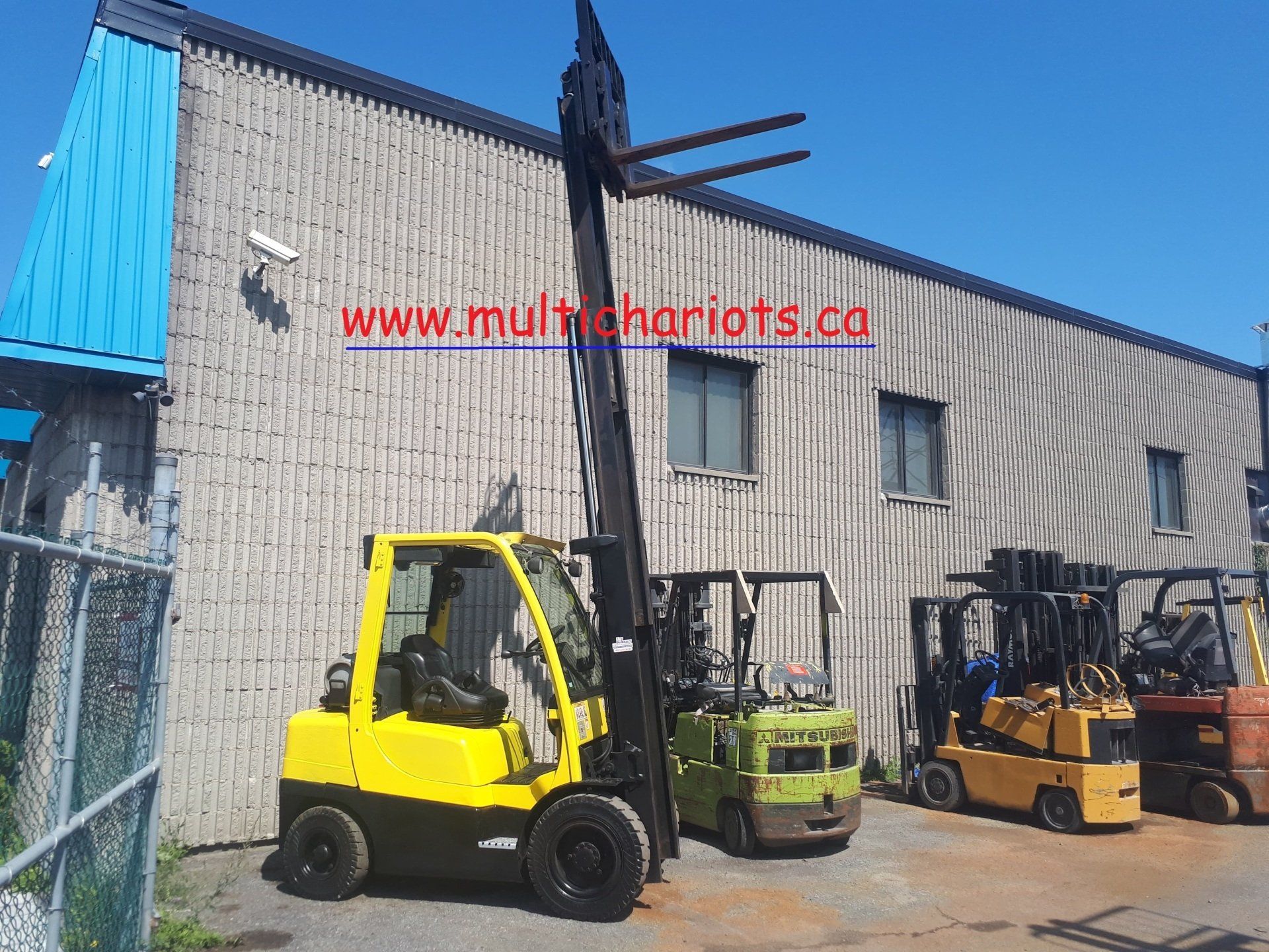 A yellow forklift is parked in front of a building.