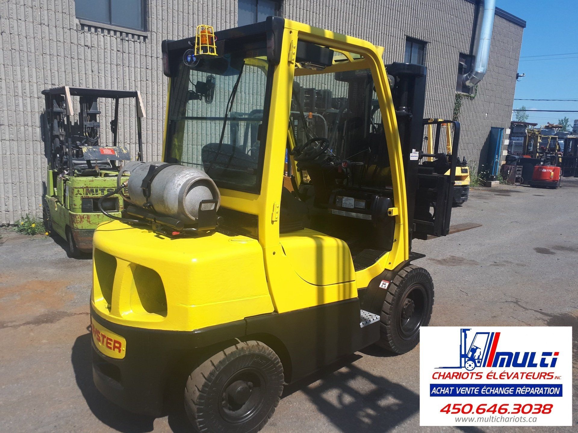 A yellow forklift is parked in front of a building