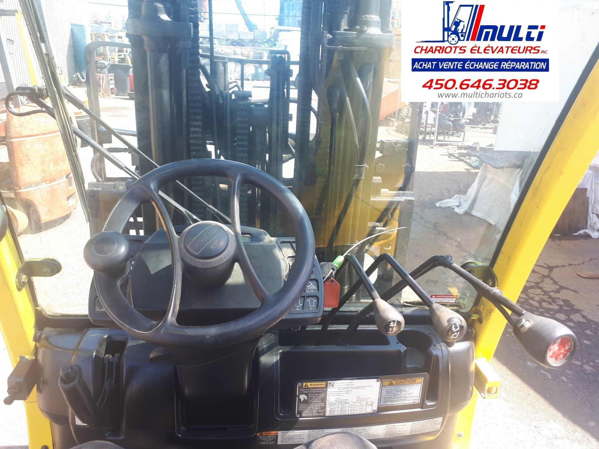 The inside of a yellow forklift with a steering wheel