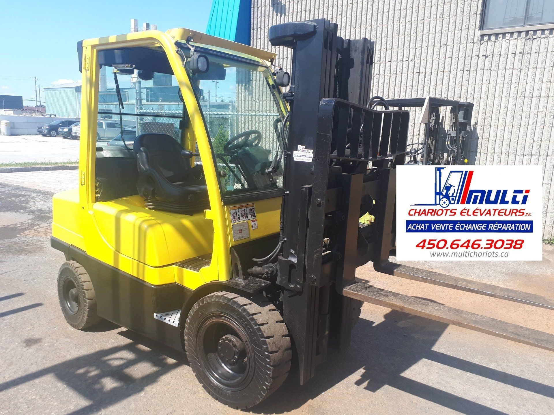 A yellow forklift is parked in front of a building