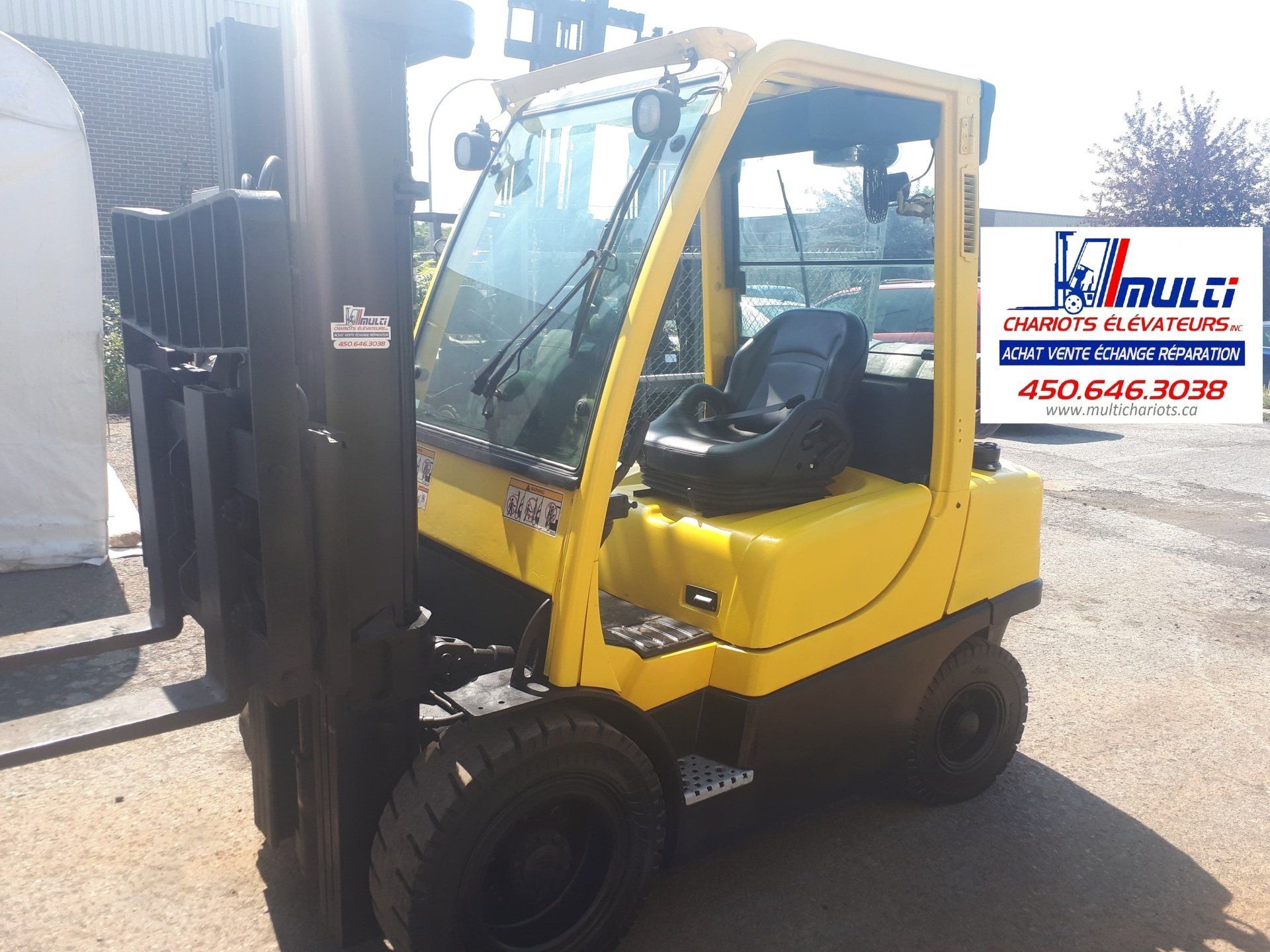 A yellow forklift is parked in front of a building