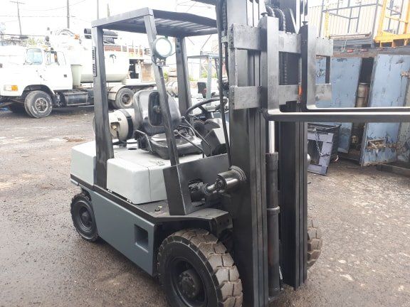 A forklift is parked in a parking lot next to a truck.