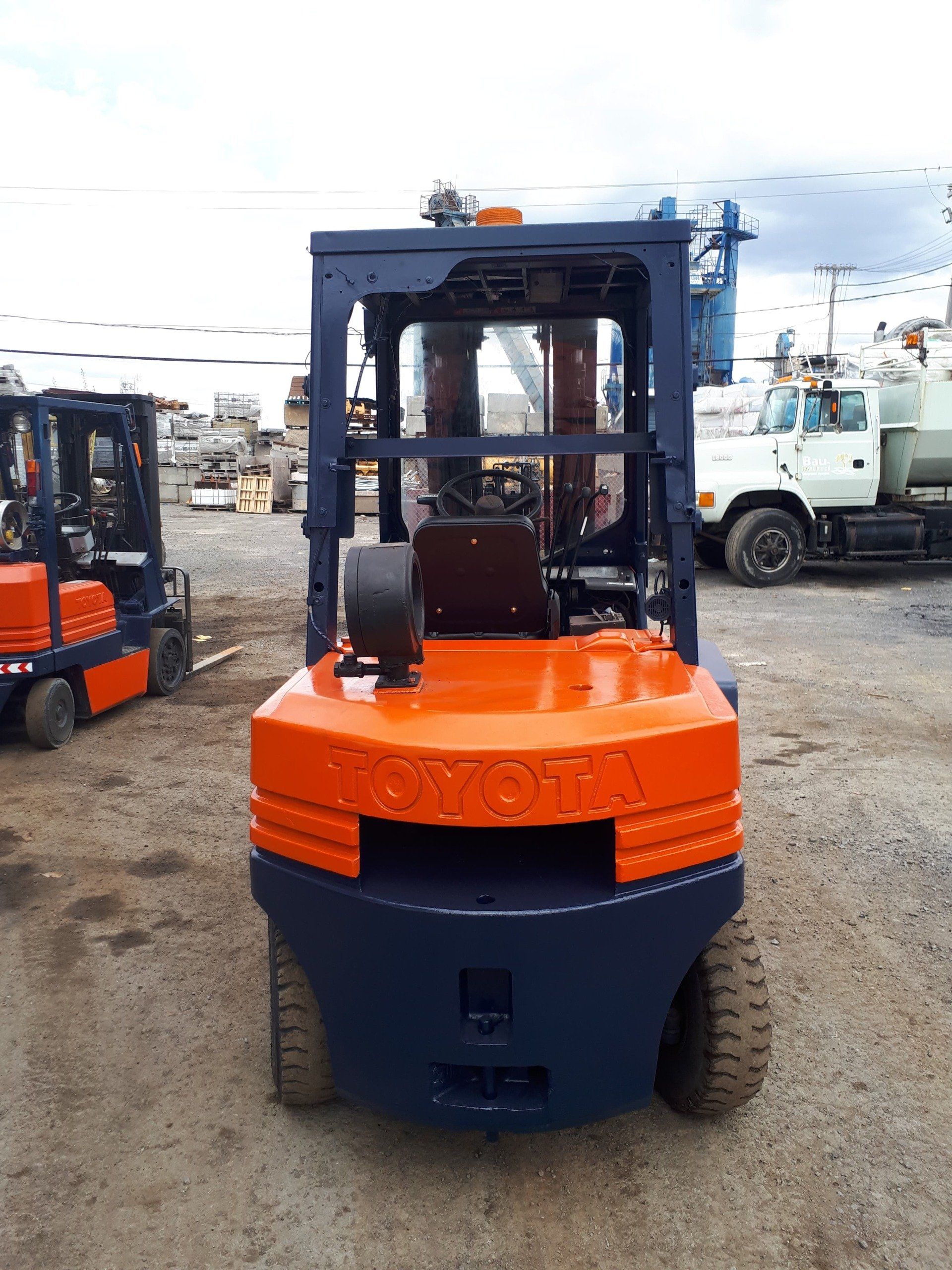 Chariot élévateur orange et bleu marine, en extérieur.