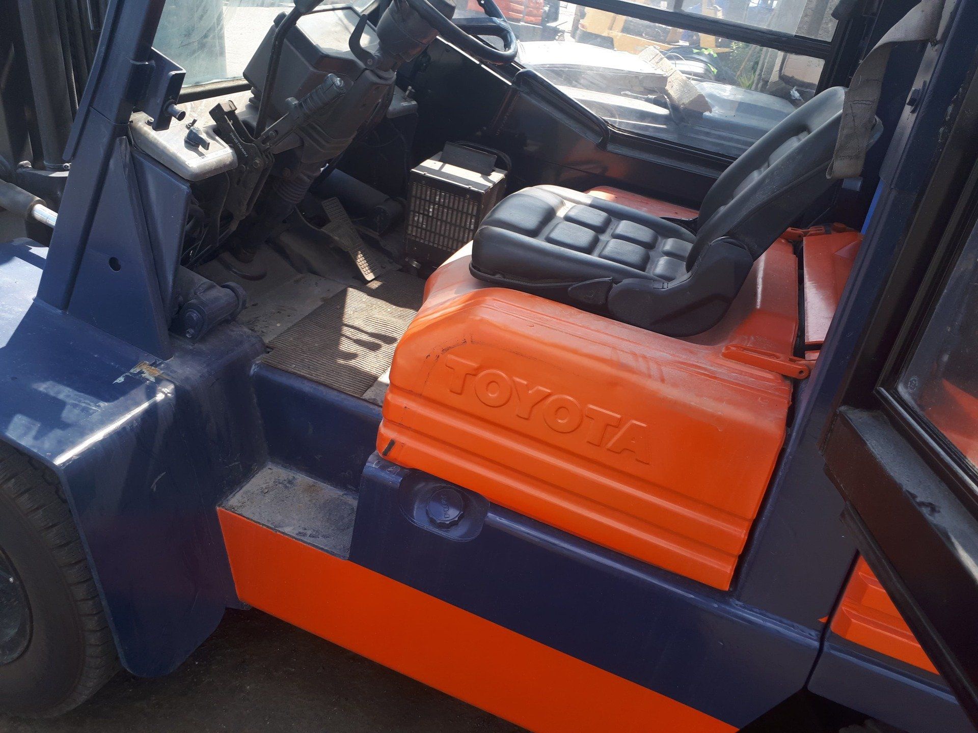 A blue and orange toyota forklift is parked on the side of the road.