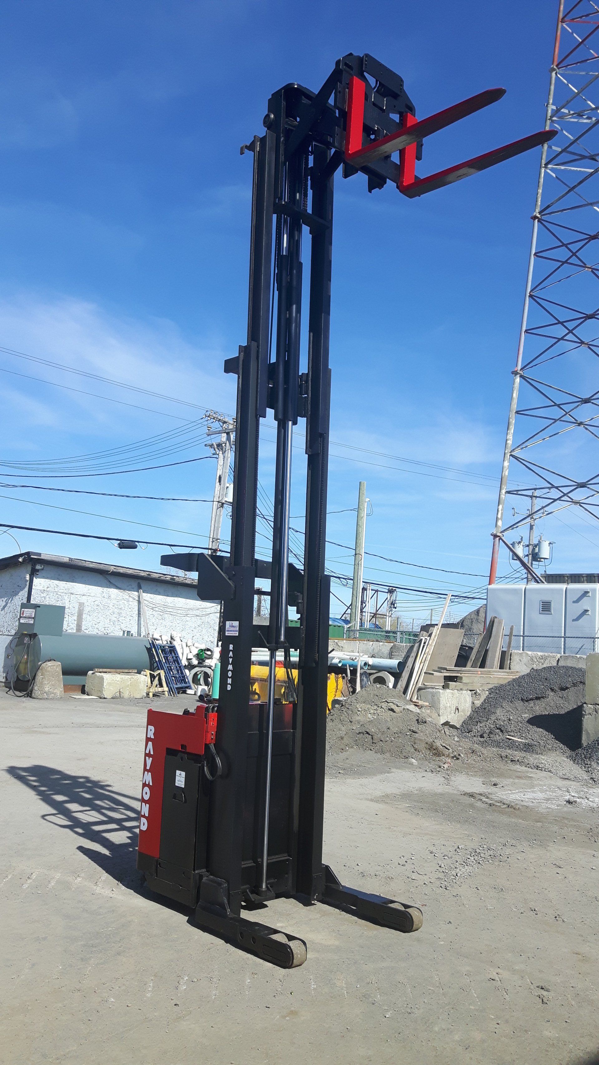 A red and black forklift is parked in a parking lot.
