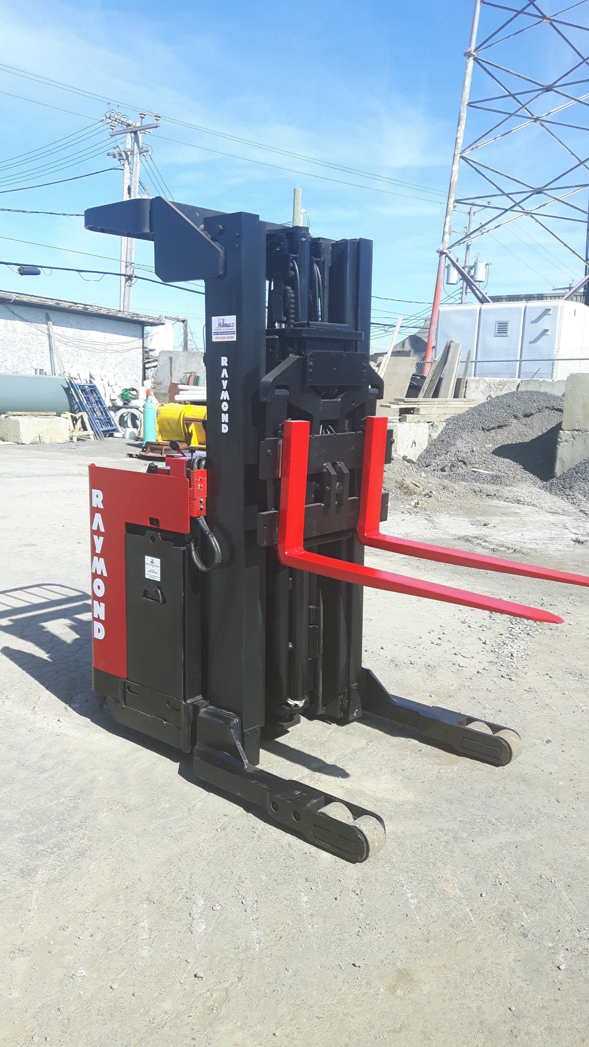 A red and black forklift is parked in a gravel lot.