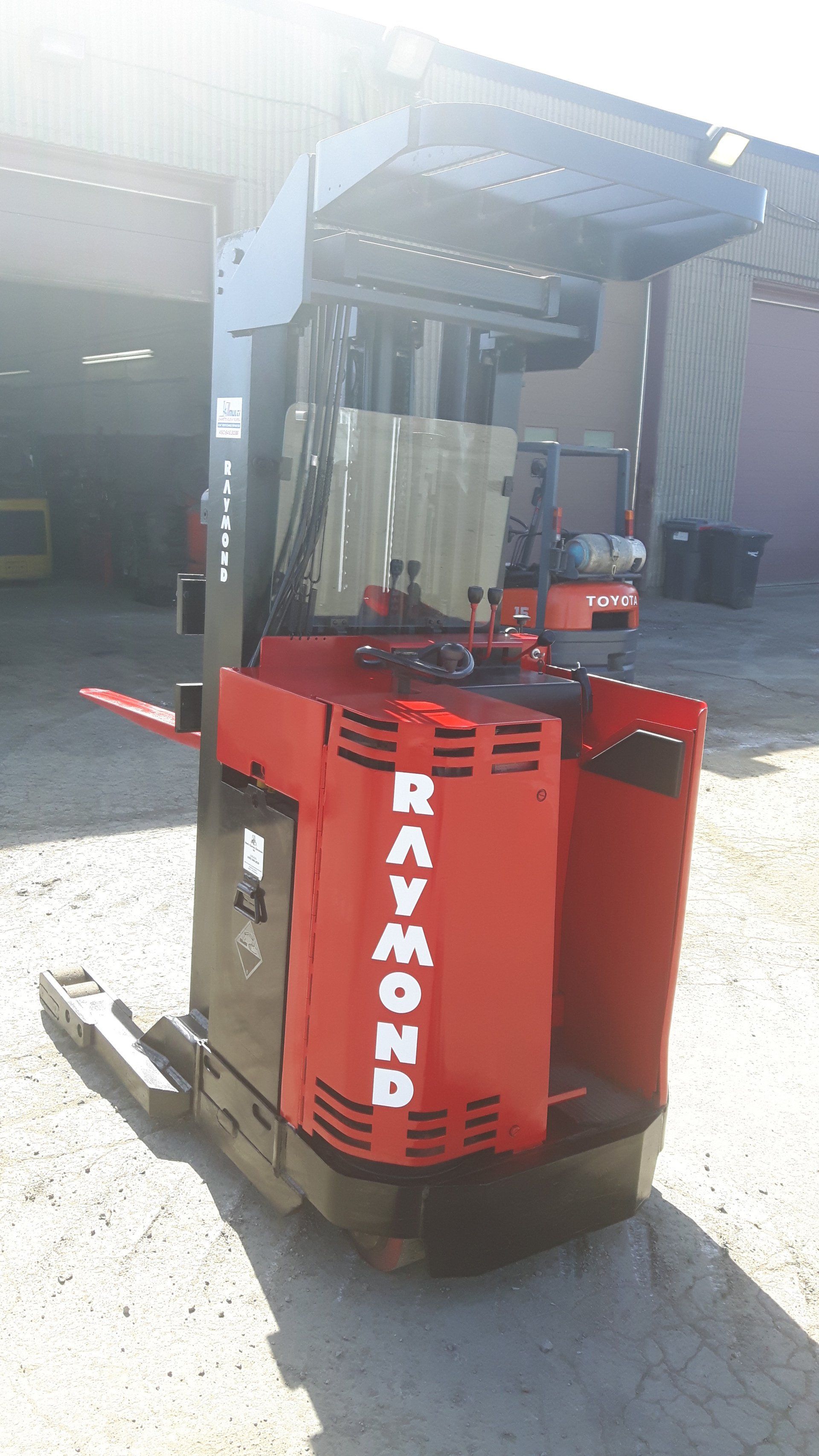 A red forklift is parked in front of a building.