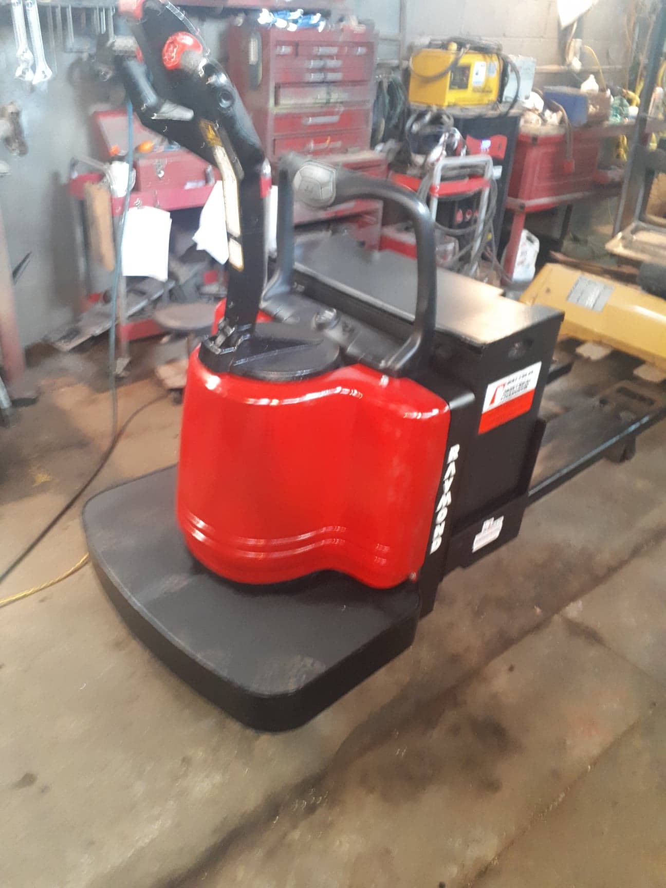 A red and black forklift is sitting in a garage