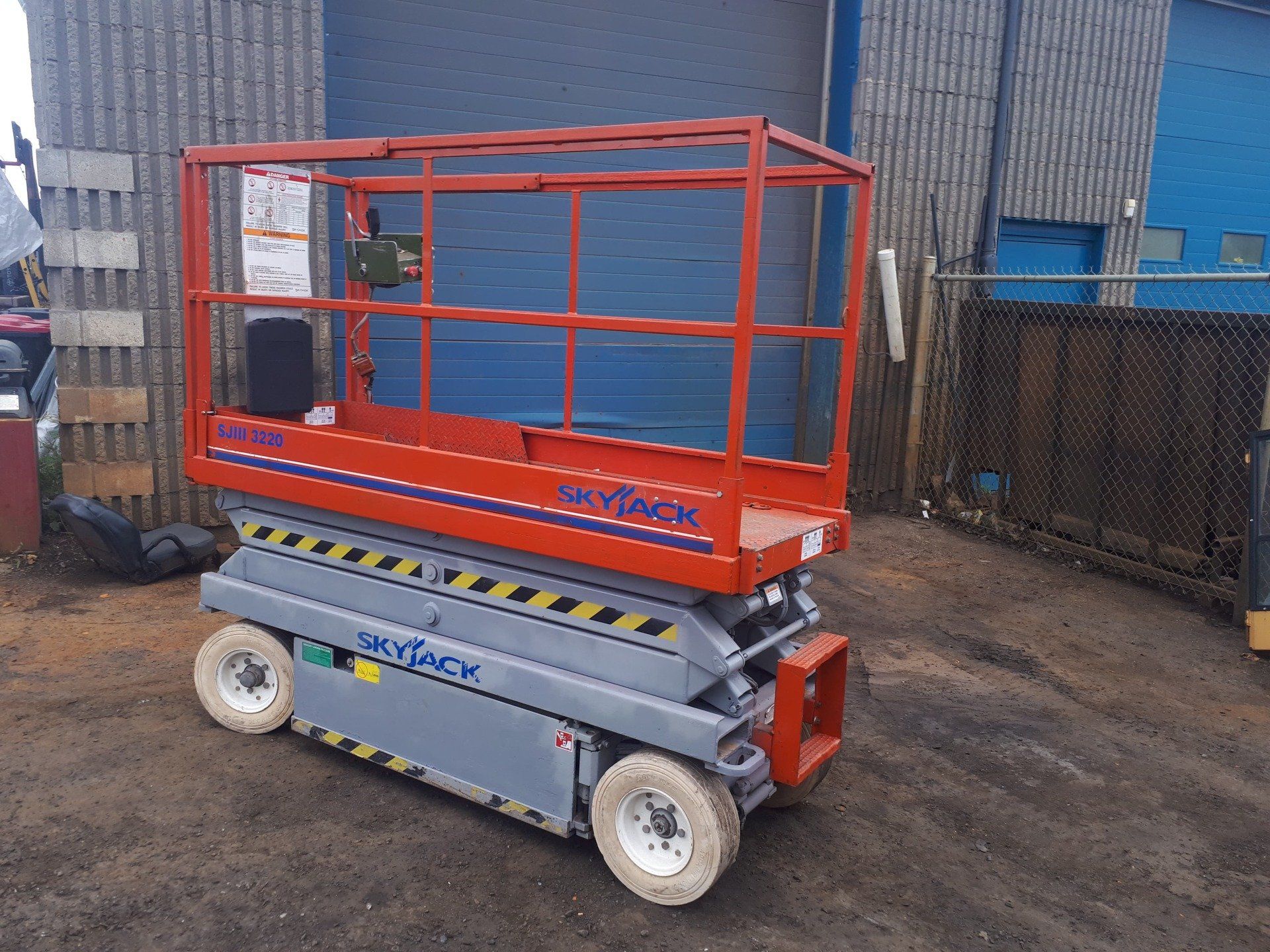 A scissor lift is parked in front of a building