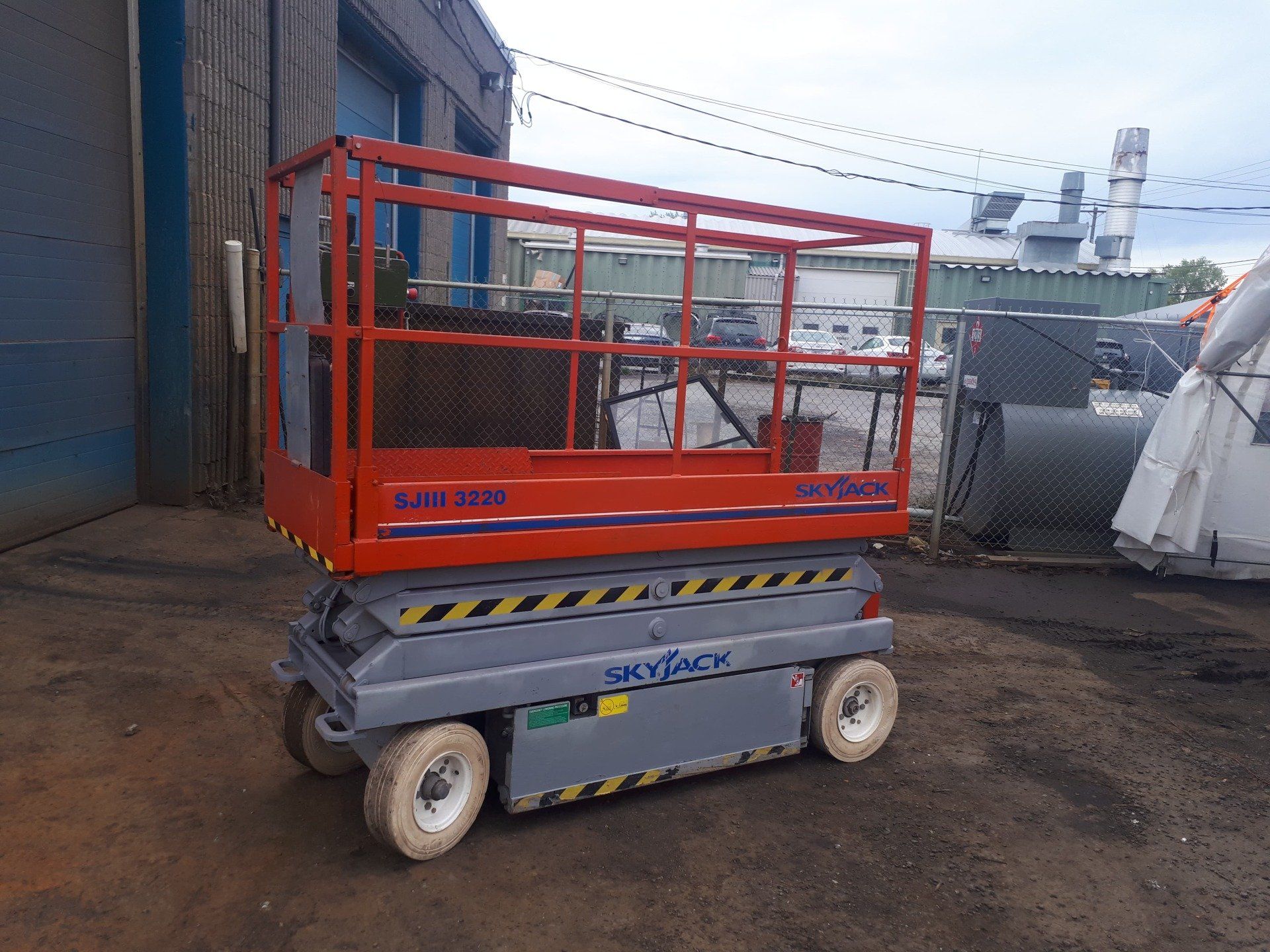 A scissor lift is parked in front of a building.