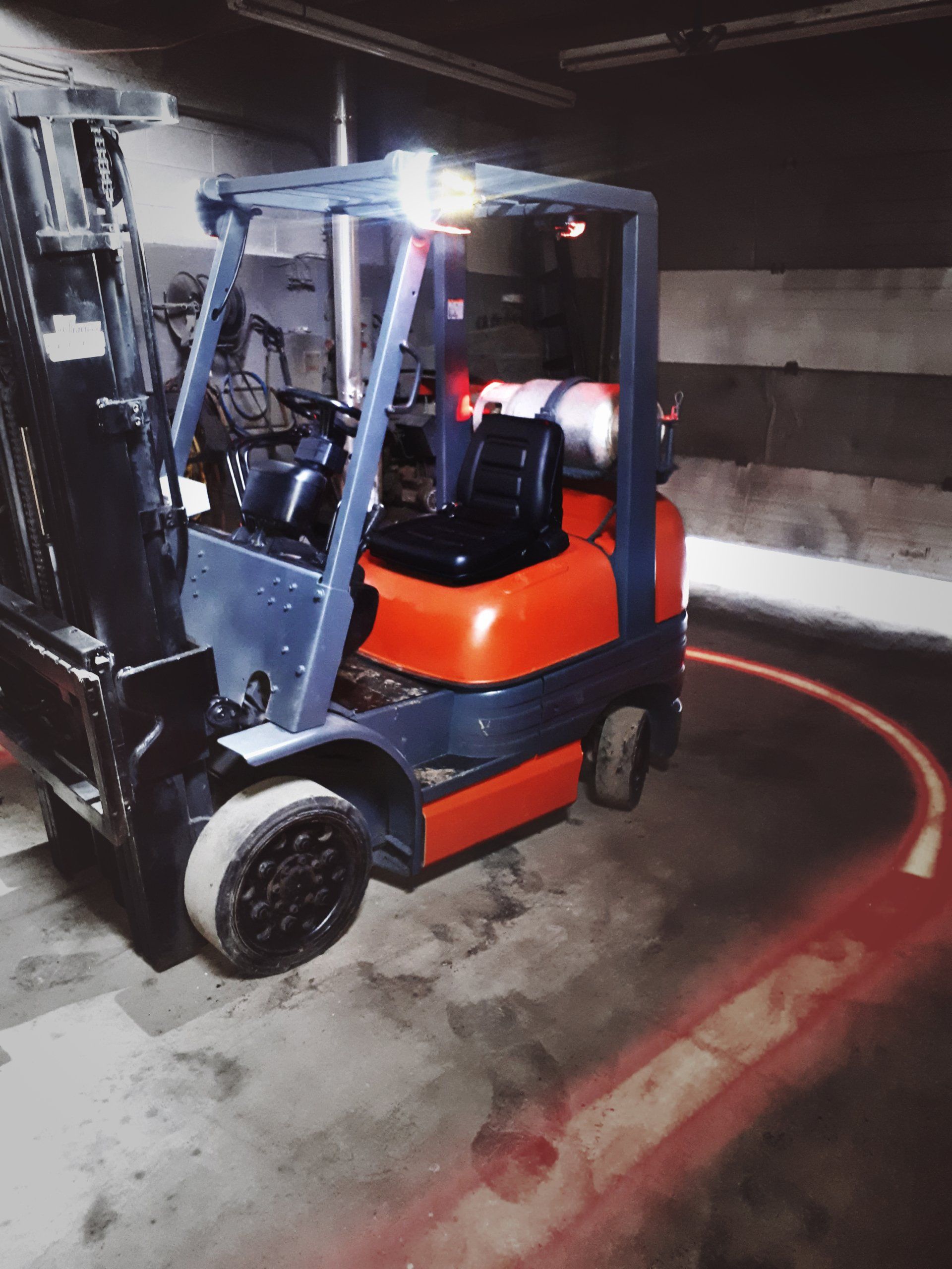 Chariot élévateur avec feu clignotant et halo de sécurité rouge dans un environnement industriel.