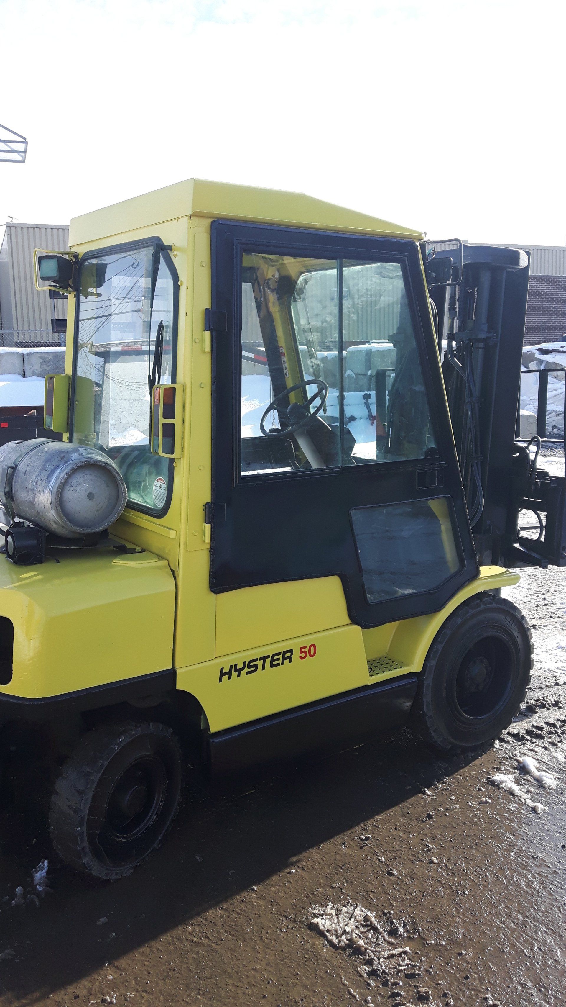 A yellow forklift is parked on the side of the road.