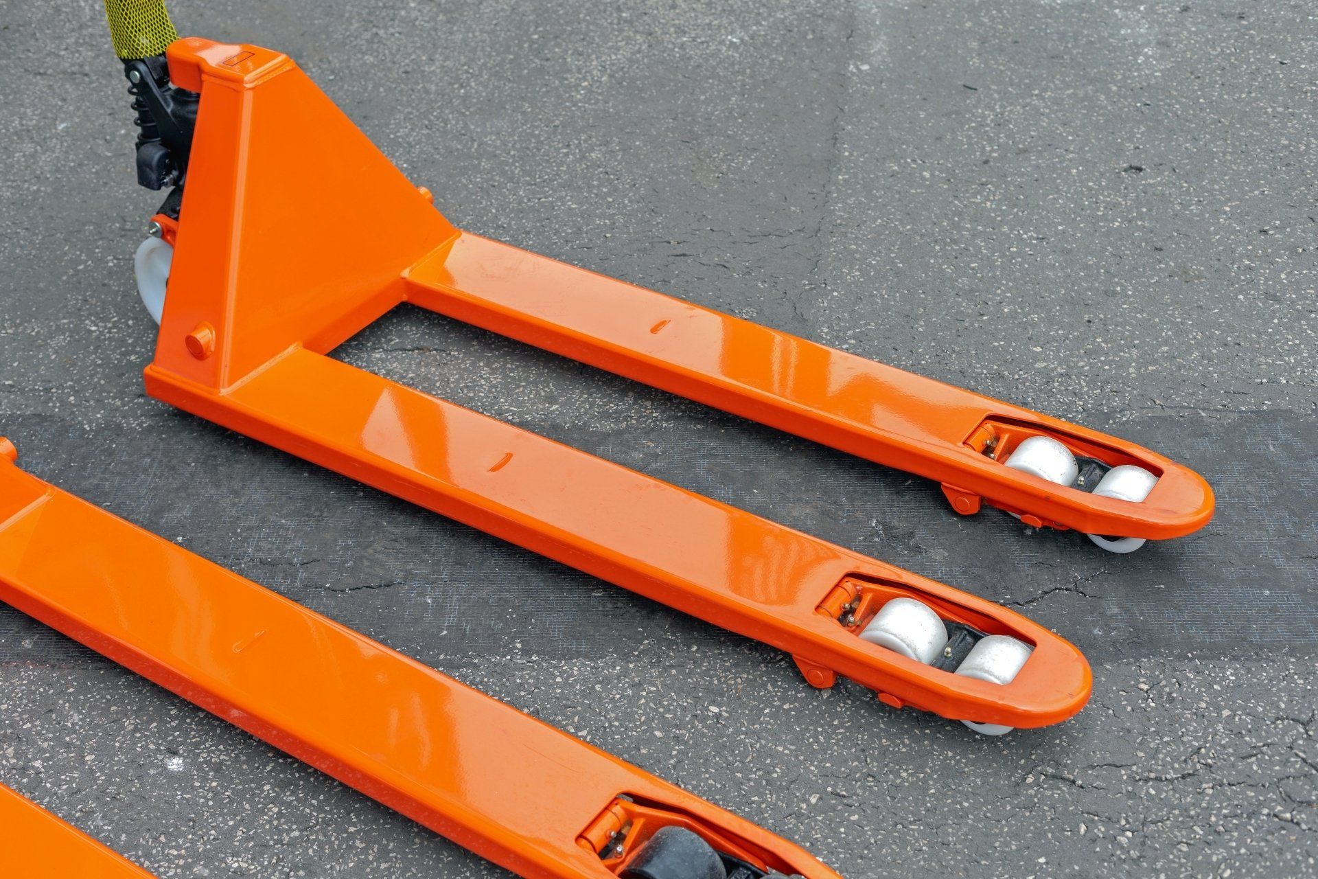 Trois transpalettes orange sont posés sur le sol.
