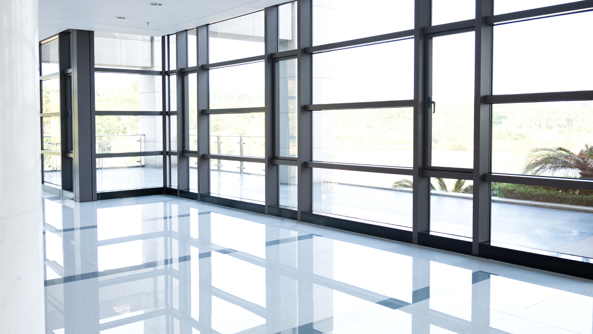 A large empty room with lots of windows and a shiny floor.
