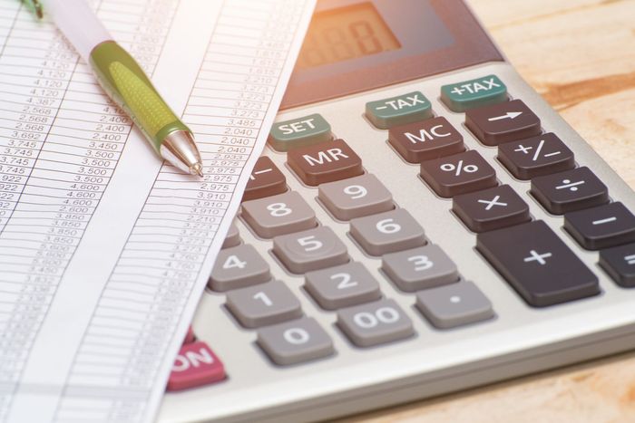 A calculator is sitting on top of a sheet of paper next to a pen. A calculator is sitting on top of a sheet of paper next to a pen.