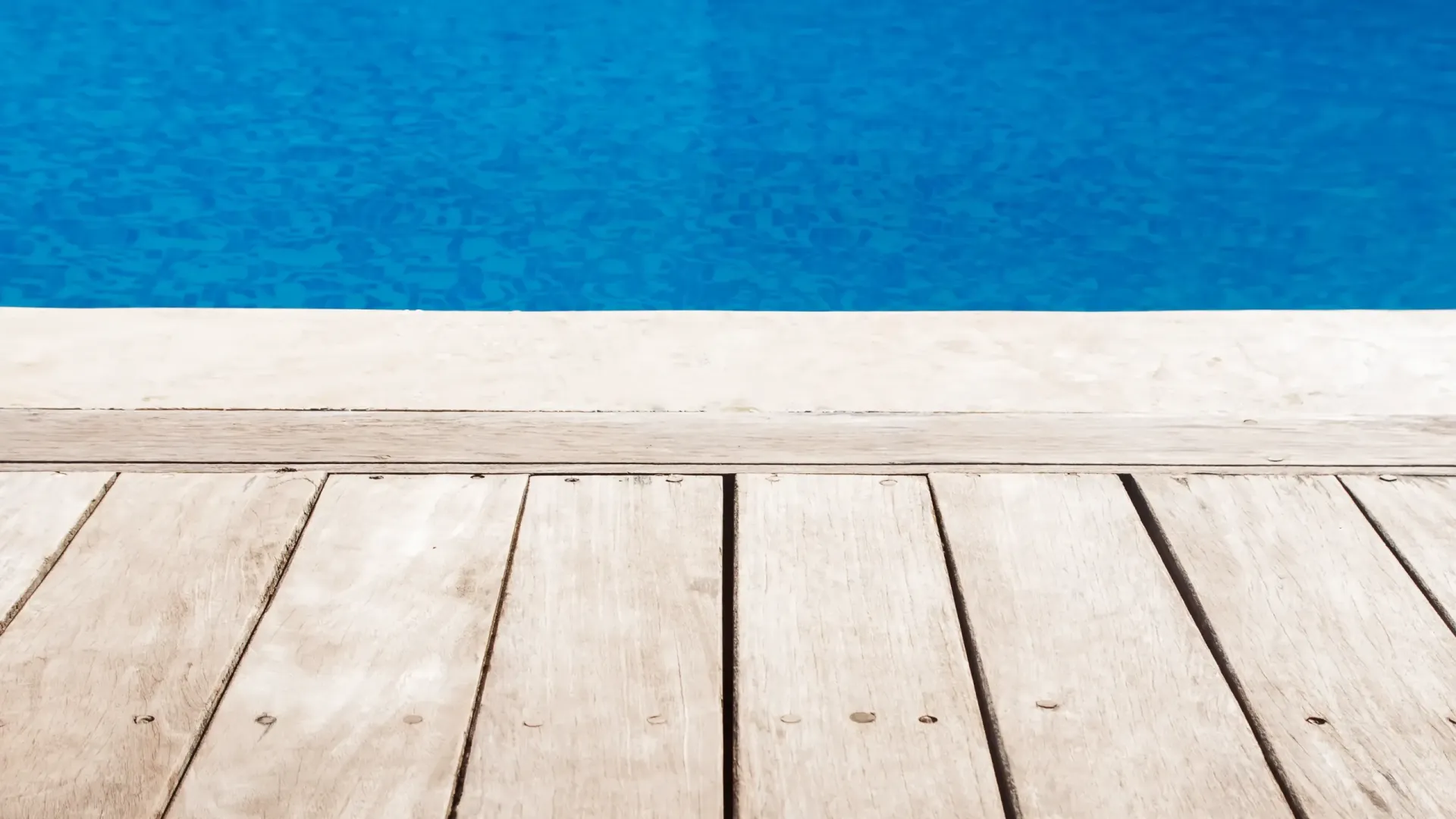 Wooden Deck Adjacent to a Bright Blue Swimming Pool — Sly Bros in Woodburn, NSW